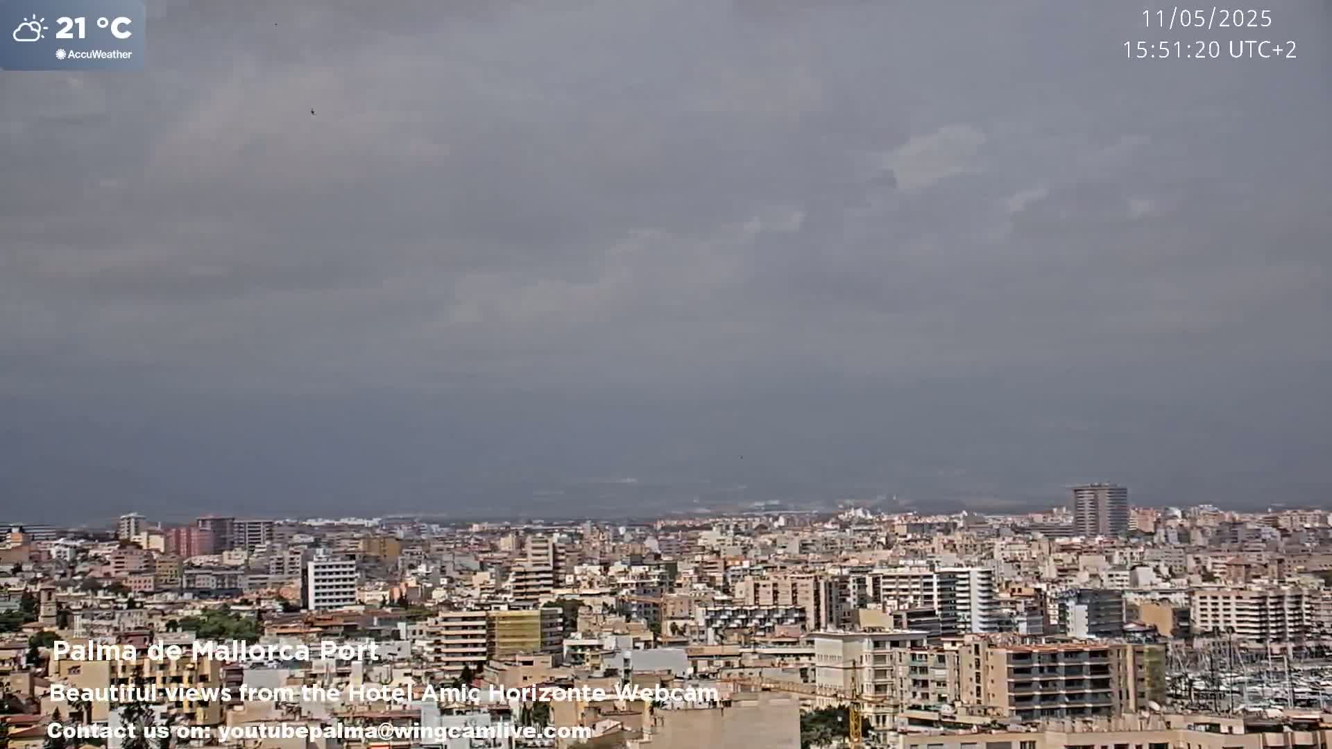 A sprawling city, under a mostly cloudy sky, is seen on a 21°C day.