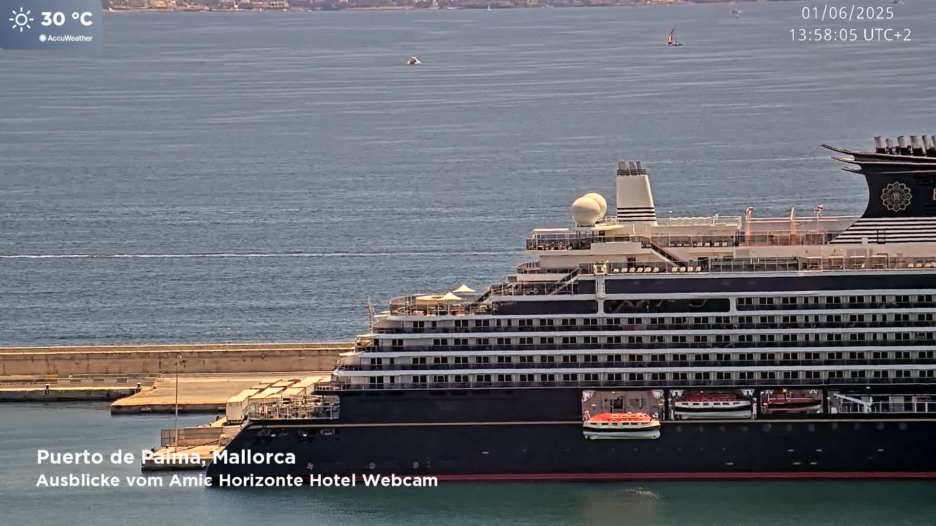A large cruise ship is docked at a port on a calm, sunny day with a water temperature of 30°C.