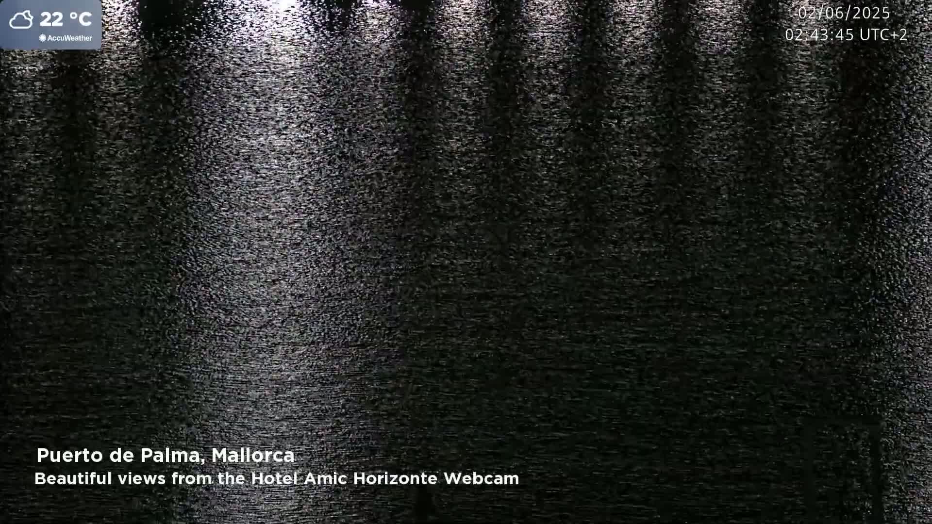A nighttime view of dark water reflecting light, with a calm surface.