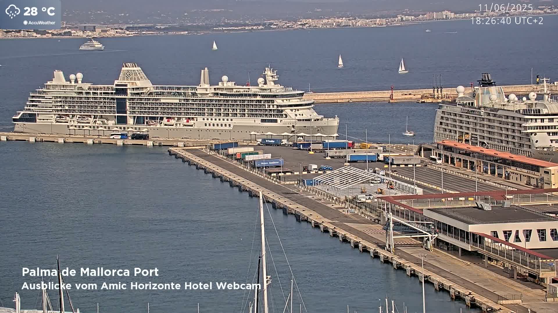 Two large cruise ships are docked at a port on a sunny day.