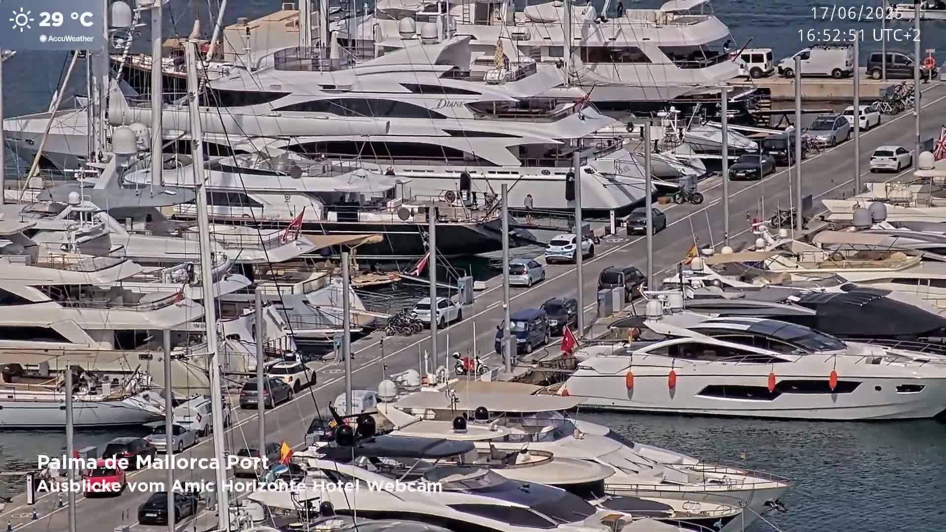 A marina filled with numerous yachts and motorboats on a sunny day with a temperature of 29°C.