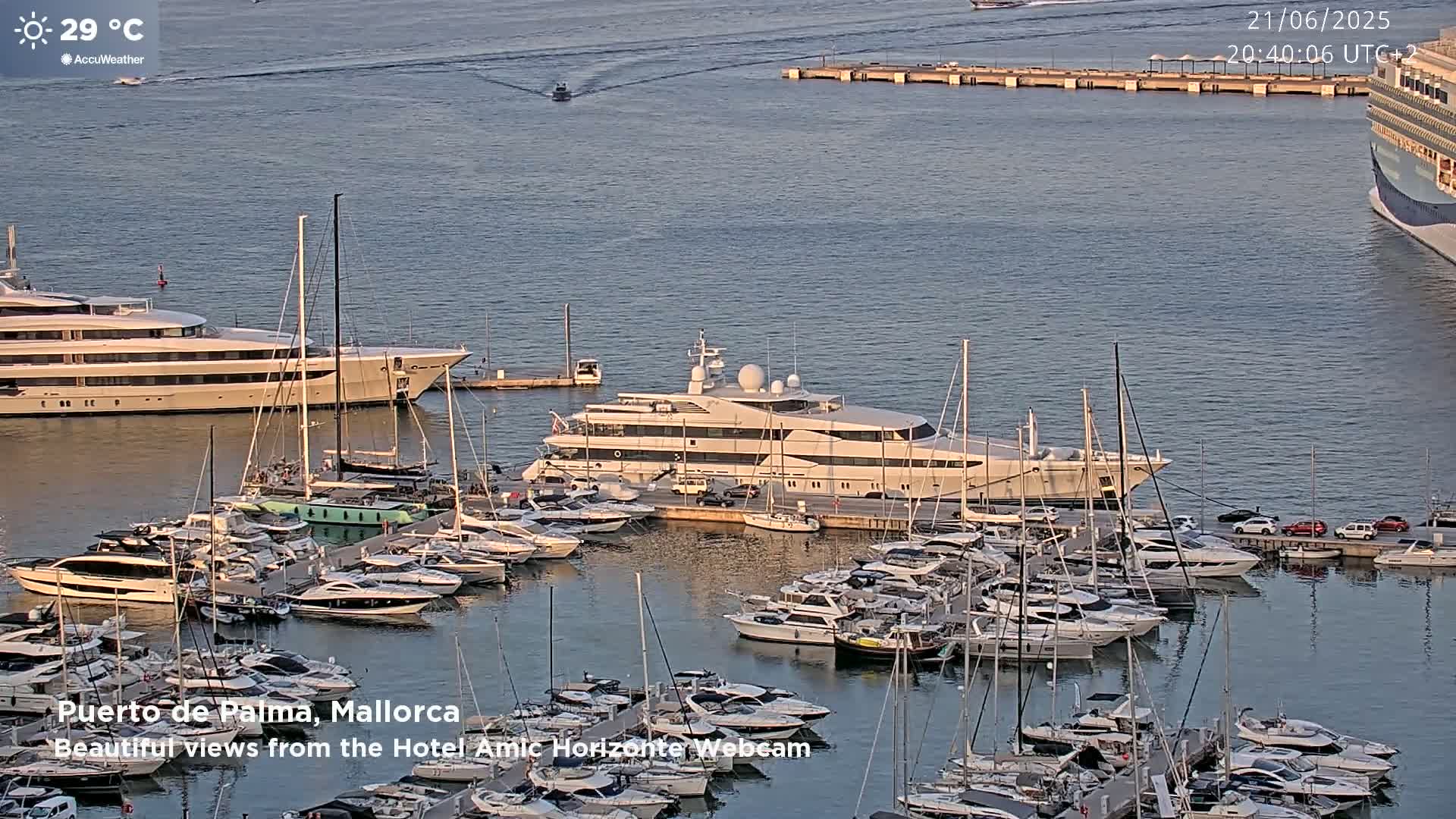 A harbor filled with numerous yachts and boats on a calm, sunny day with a temperature of 29°C.