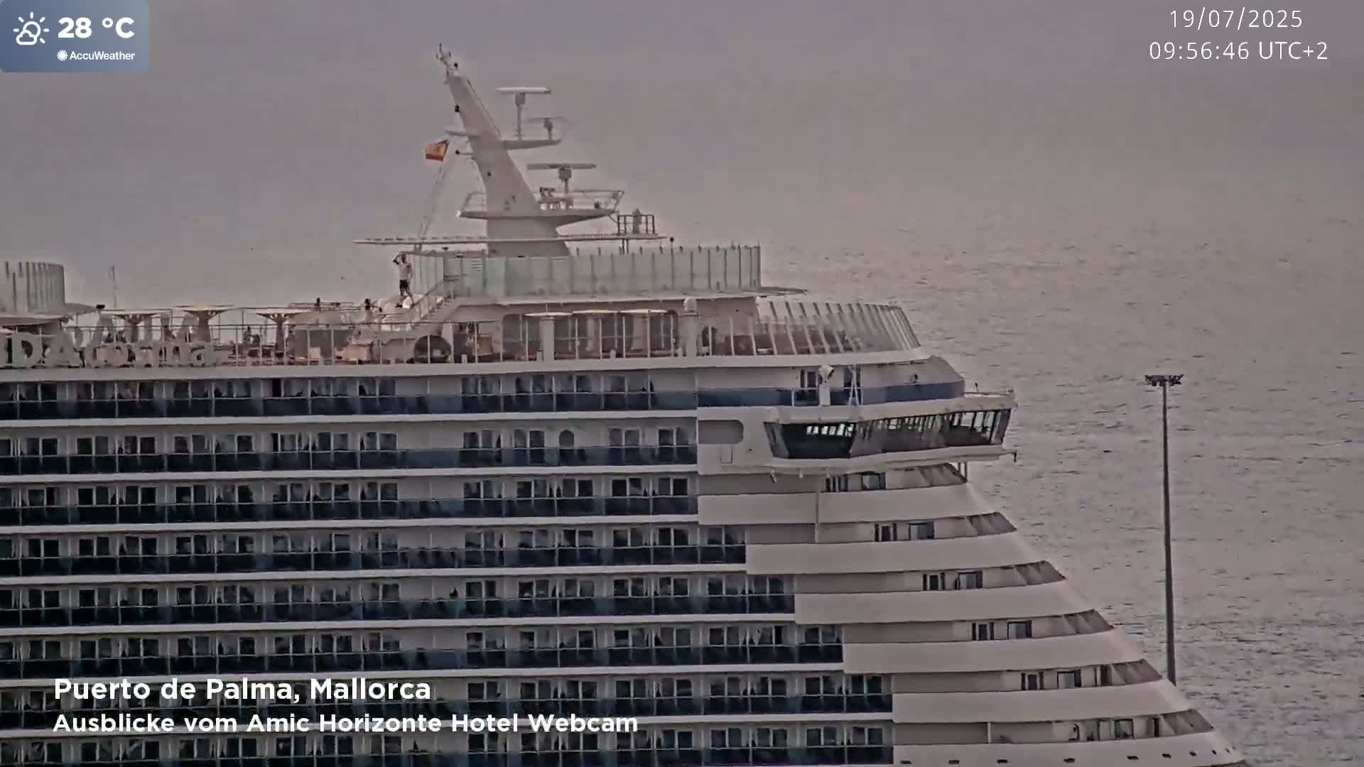 A large cruise ship is docked in calm water on an overcast day.