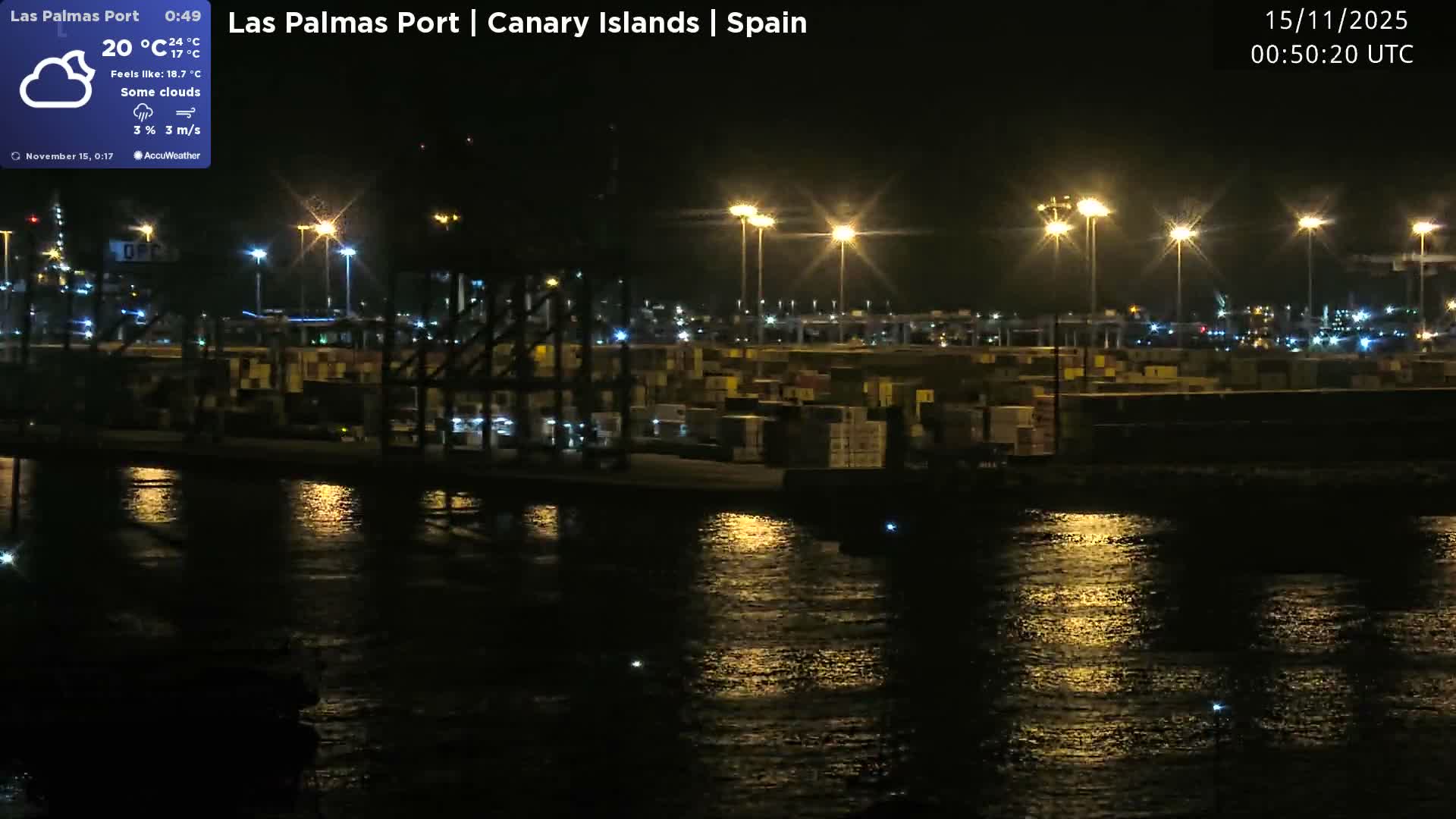 A bustling port scene at night shows stacks of shipping containers and numerous bright industrial lights reflecting on the calm water.
