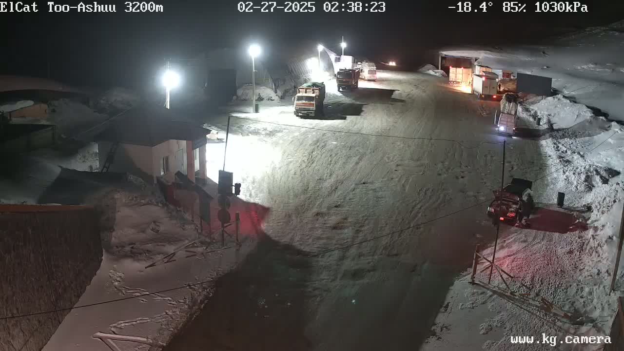 Several trucks are parked in a snow-covered lot at night, under bright lights, in -18.4°C weather with 85% humidity.