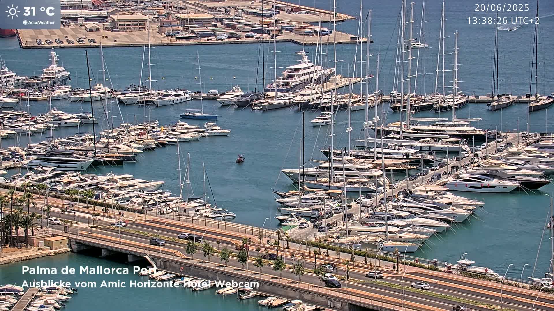 A marina filled with numerous yachts and sailboats on a sunny day with a temperature of 31°C.