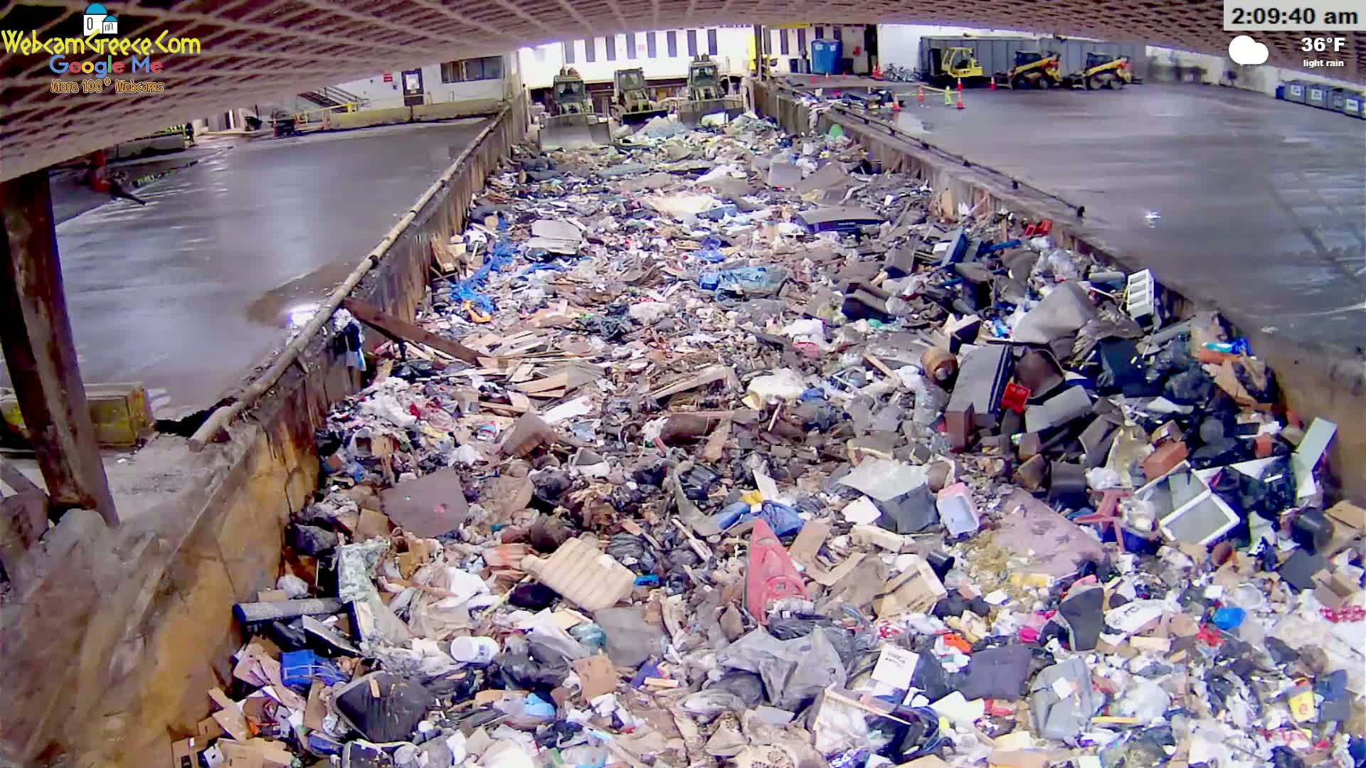 A large pile of refuse sits inside a concrete structure during light rain.