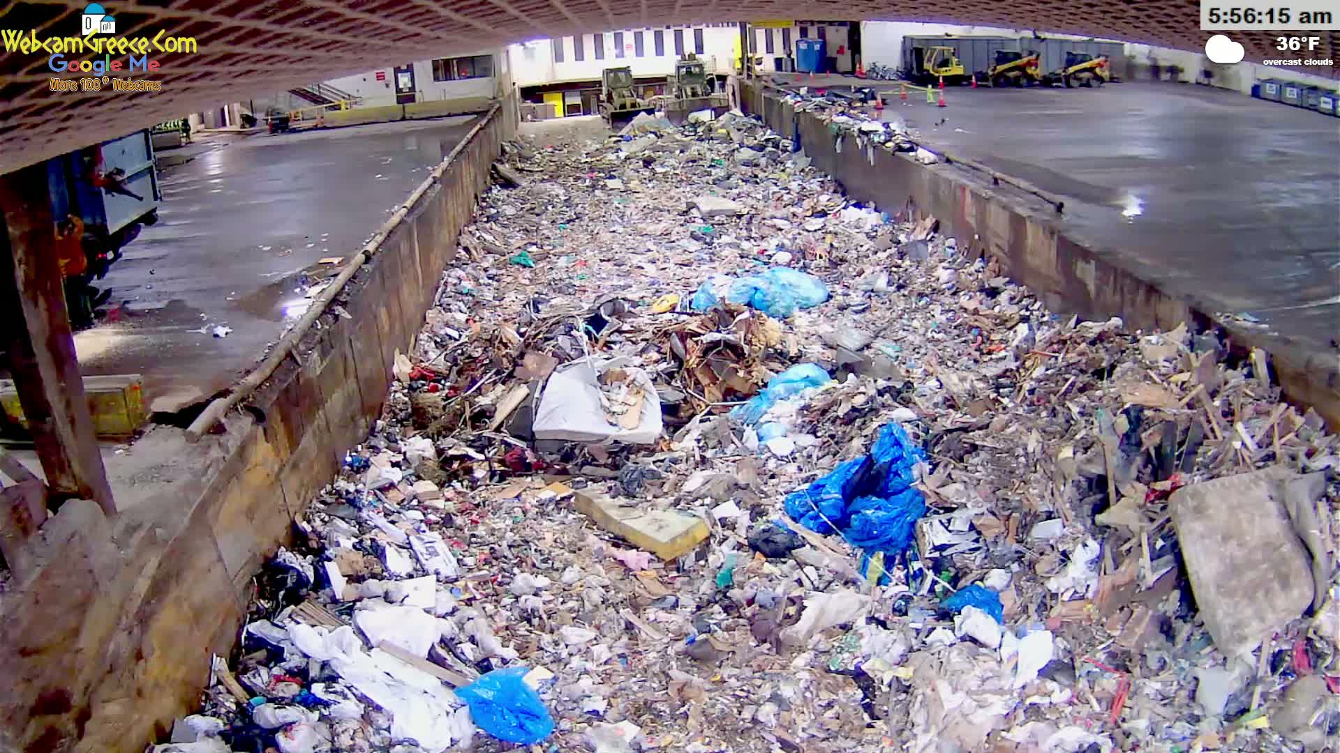 A large pile of trash and debris fills a concrete trough under overcast skies.