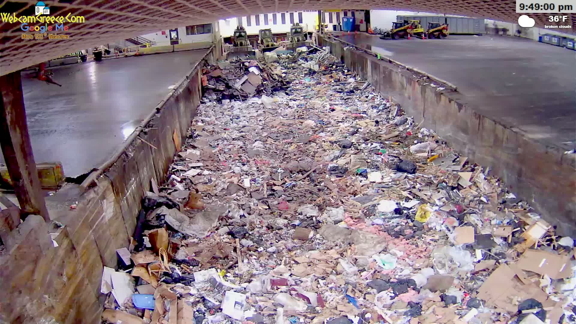 A large pile of trash fills a concrete-walled trough outdoors under broken clouds at 36°F.