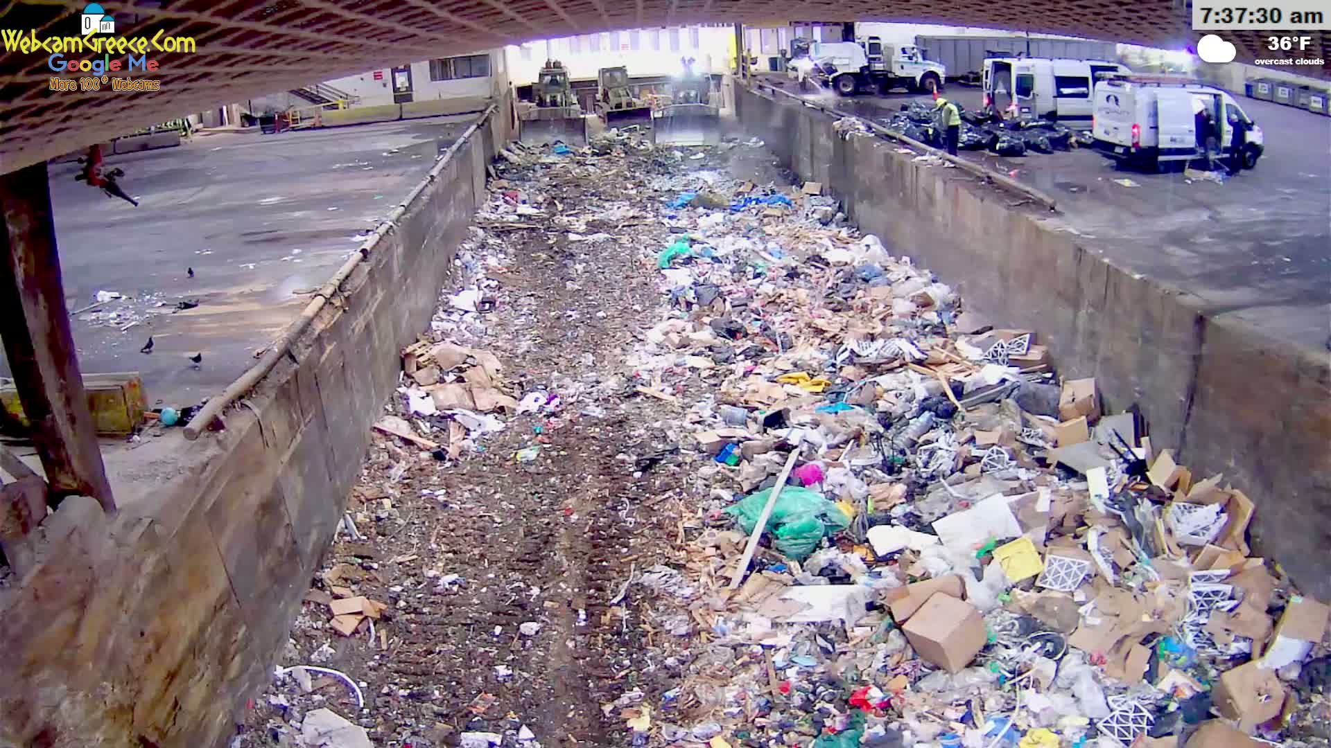 A large pile of trash fills a concrete trough outdoors on an overcast day at 36°F.