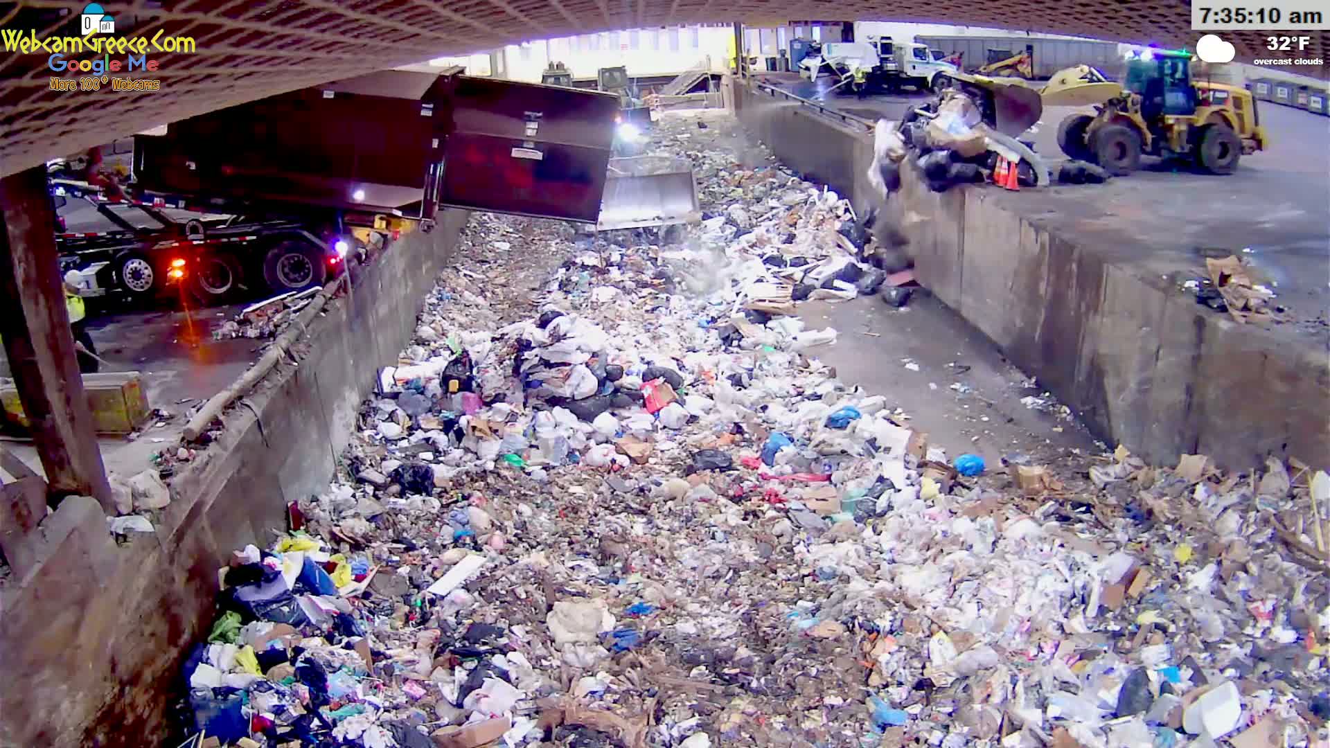 A large pile of garbage is being dumped from a truck into a concrete chute under overcast skies at 32°F.