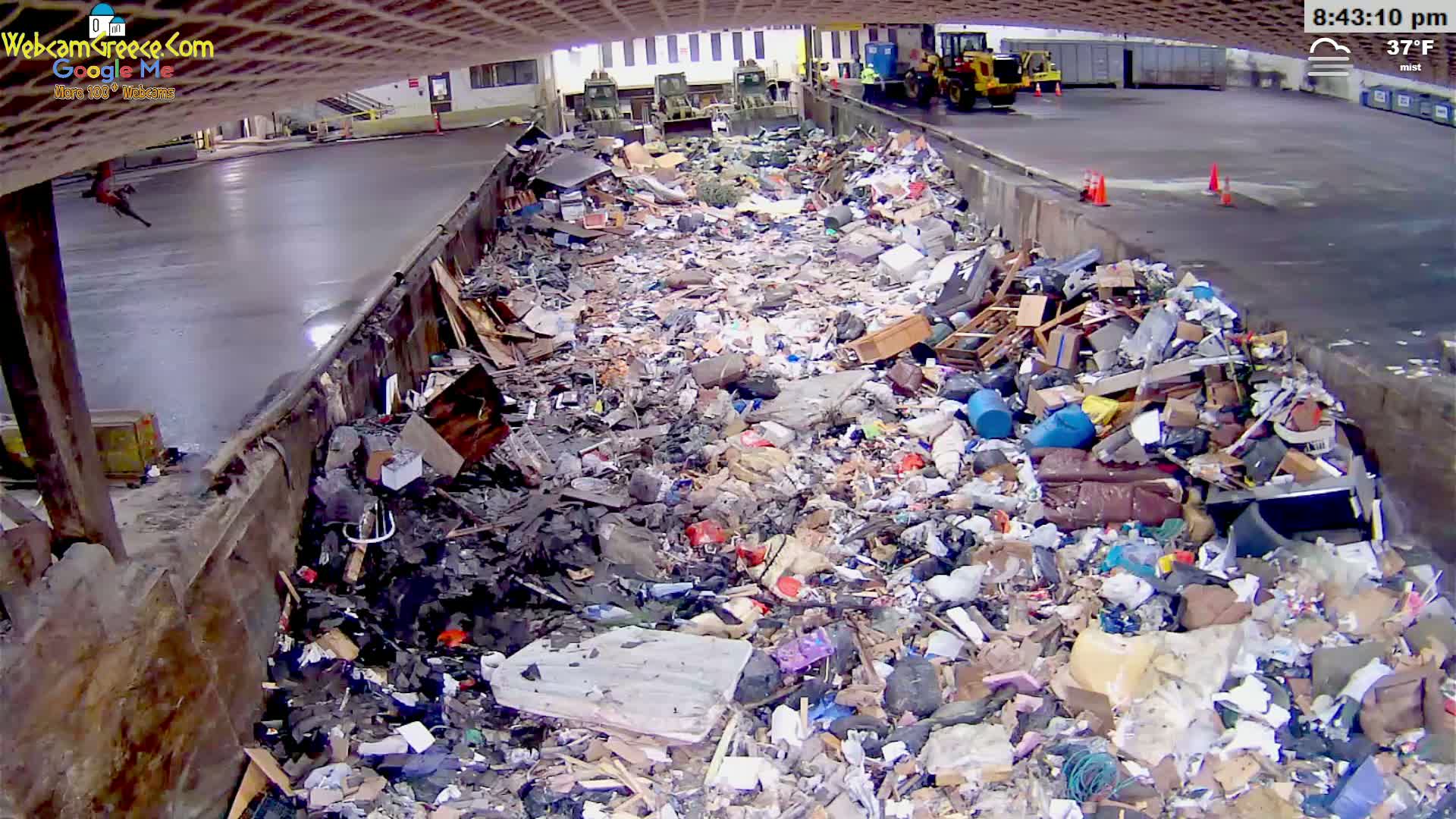 A large pile of refuse sits in an outdoor waste disposal area under a misty sky, with a temperature of 37°F.