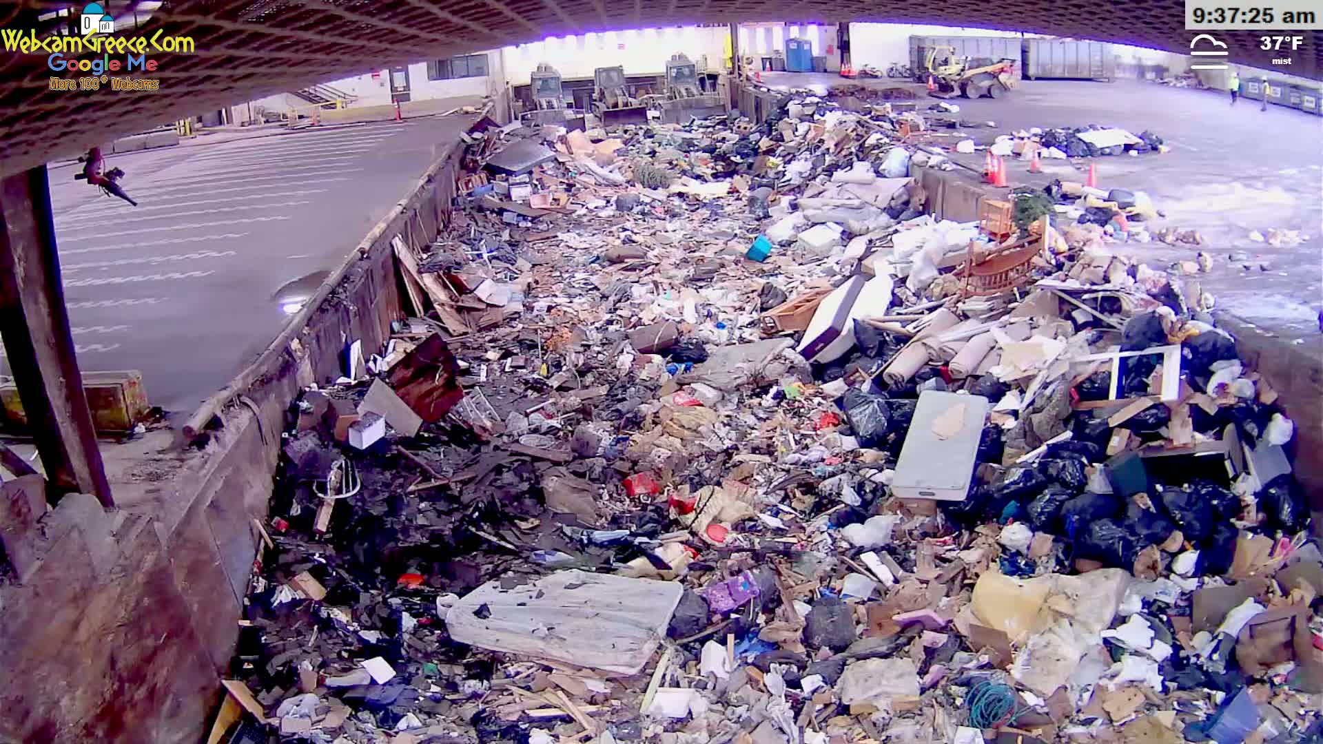 A large pile of refuse sits in a misty, 37°F outdoor waste disposal area.