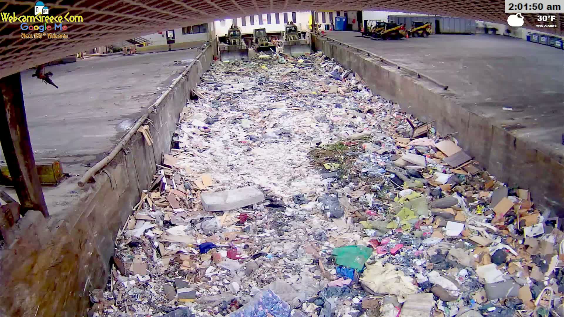 A large pile of trash fills a concrete trough outdoors under a few clouds with a temperature of 30°F.