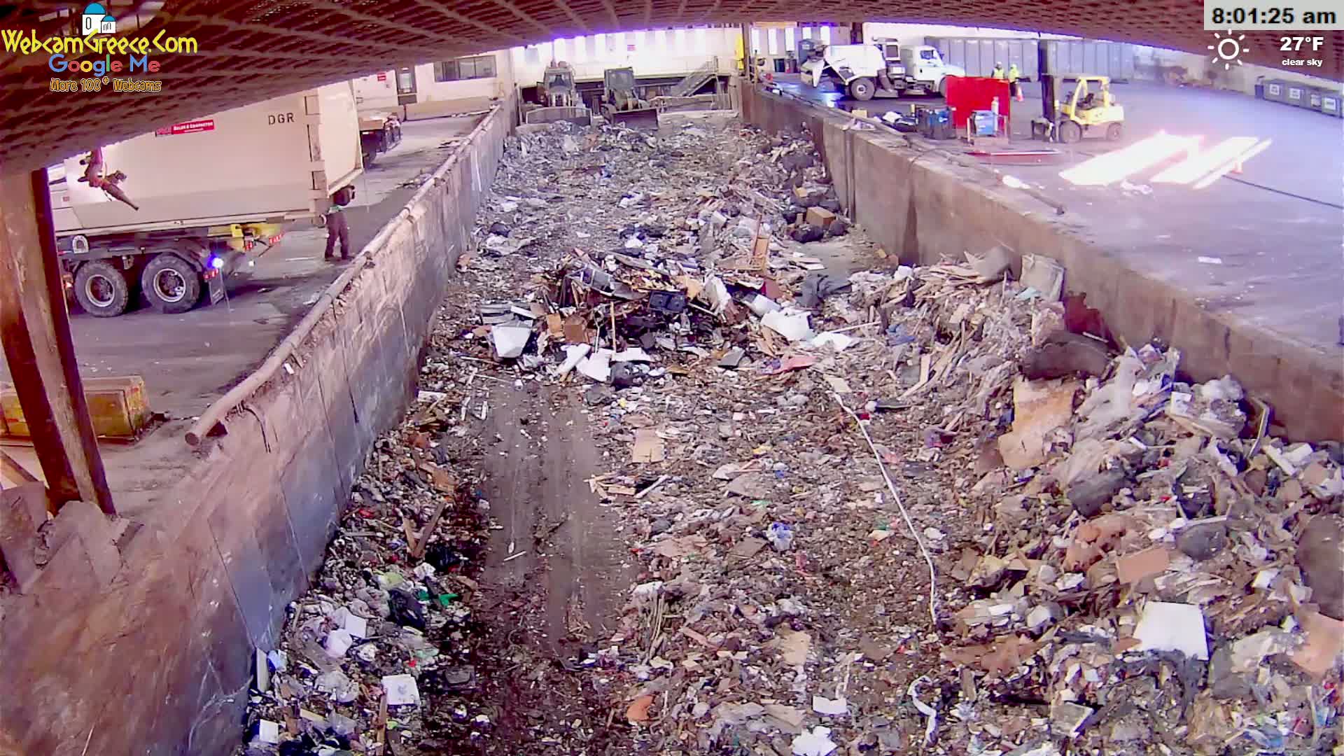 A large pile of trash and debris fills a long, concrete-walled trough outdoors on a clear, 27°F day.