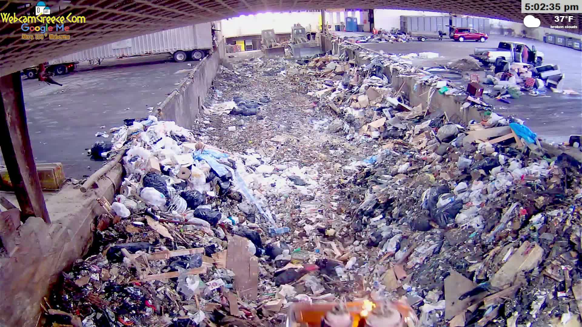 A large pile of trash sits in an outdoor refuse area under broken clouds, with a temperature of 37°F.
