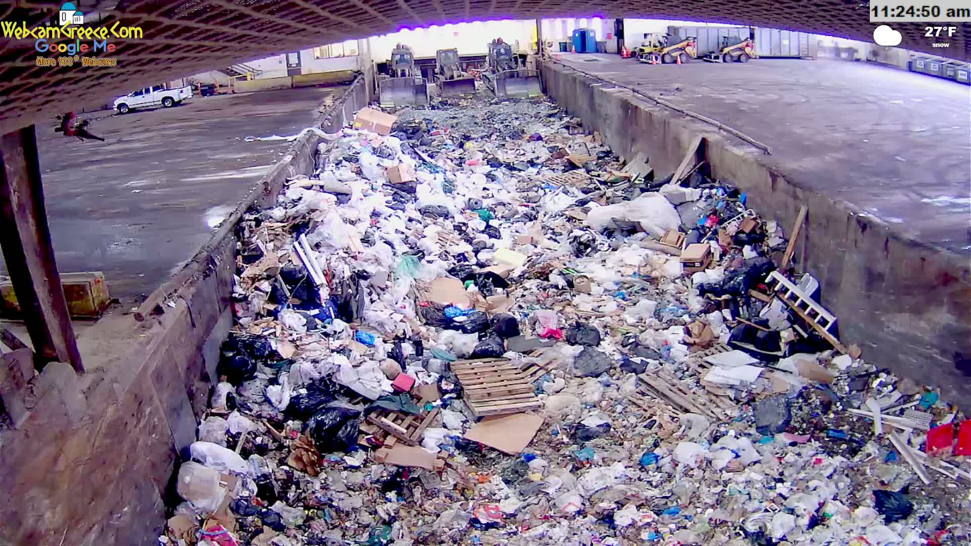 A large pile of trash is seen in an outdoor waste disposal area on a snowy 27°F day.