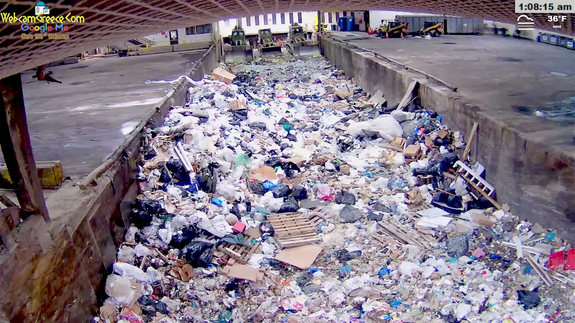 A large pile of garbage sits in a concrete trough outdoors in misty 36°F weather.