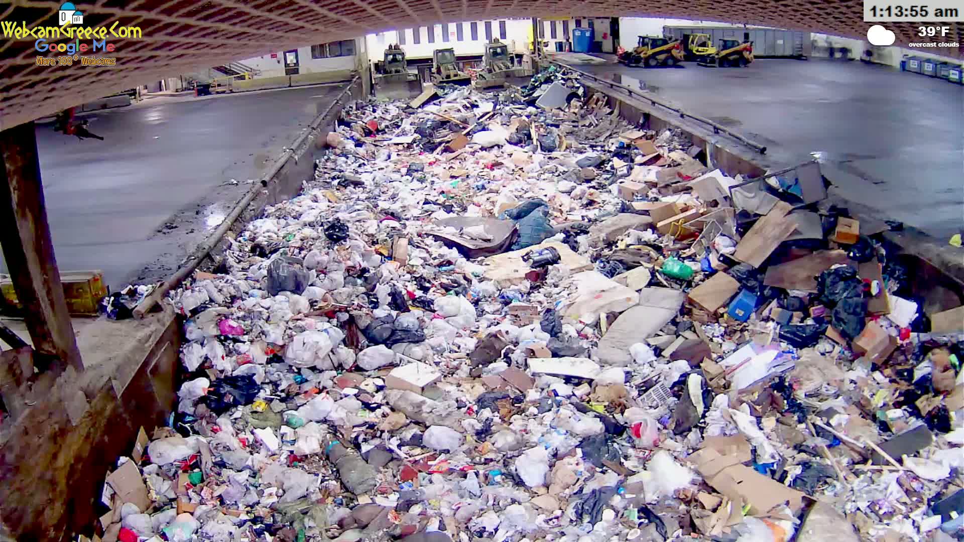 A large pile of garbage sits in a concrete trough under overcast skies.