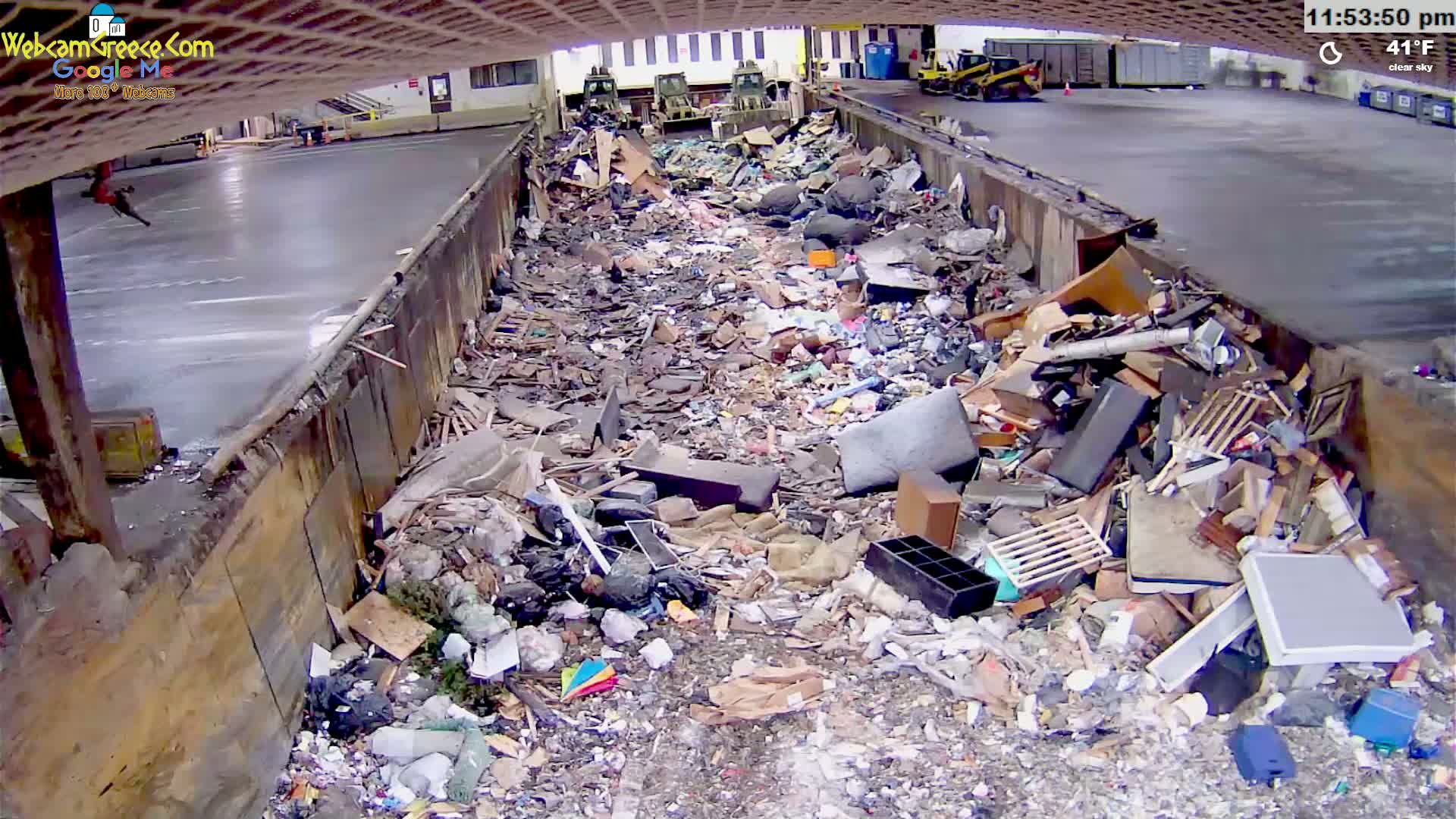 A large pile of refuse and debris fills a long, narrow container outdoors under a clear sky at 41°F.