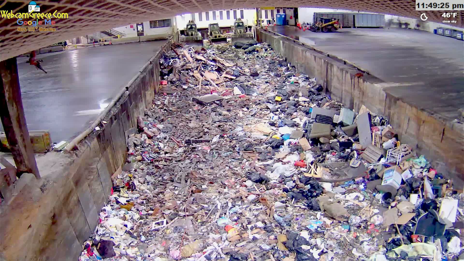 A large pile of refuse sits in a concrete-walled pit under a clear sky at 46°F.