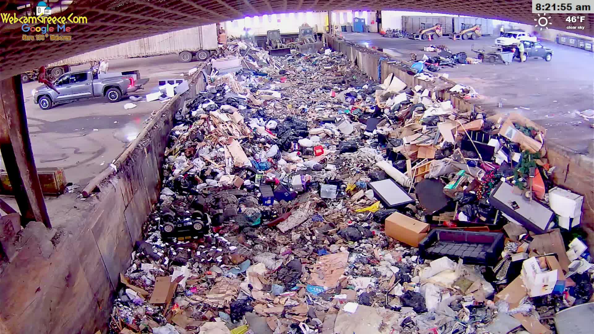 A large pile of assorted trash and debris fills a waste disposal area on a clear, 46°F morning.