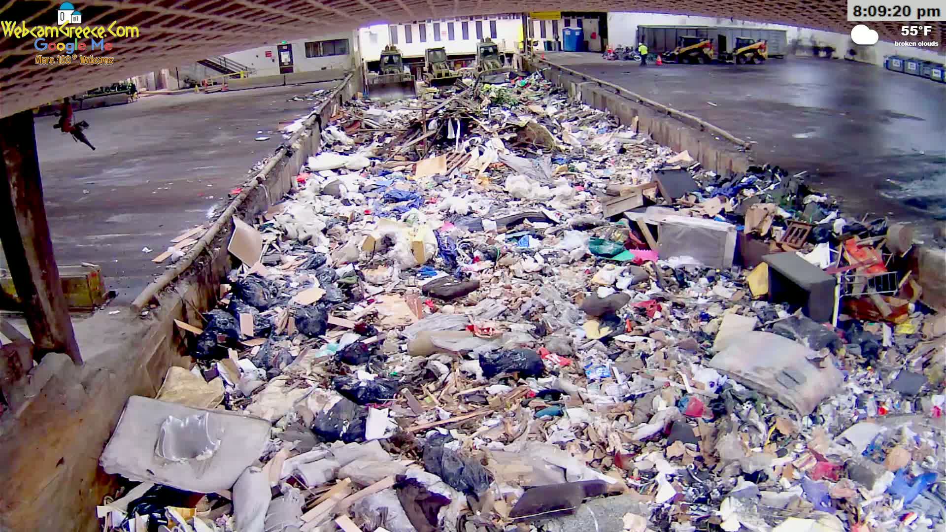 A large pile of mixed garbage sits in an outdoor loading area under broken clouds and a 55°F temperature.