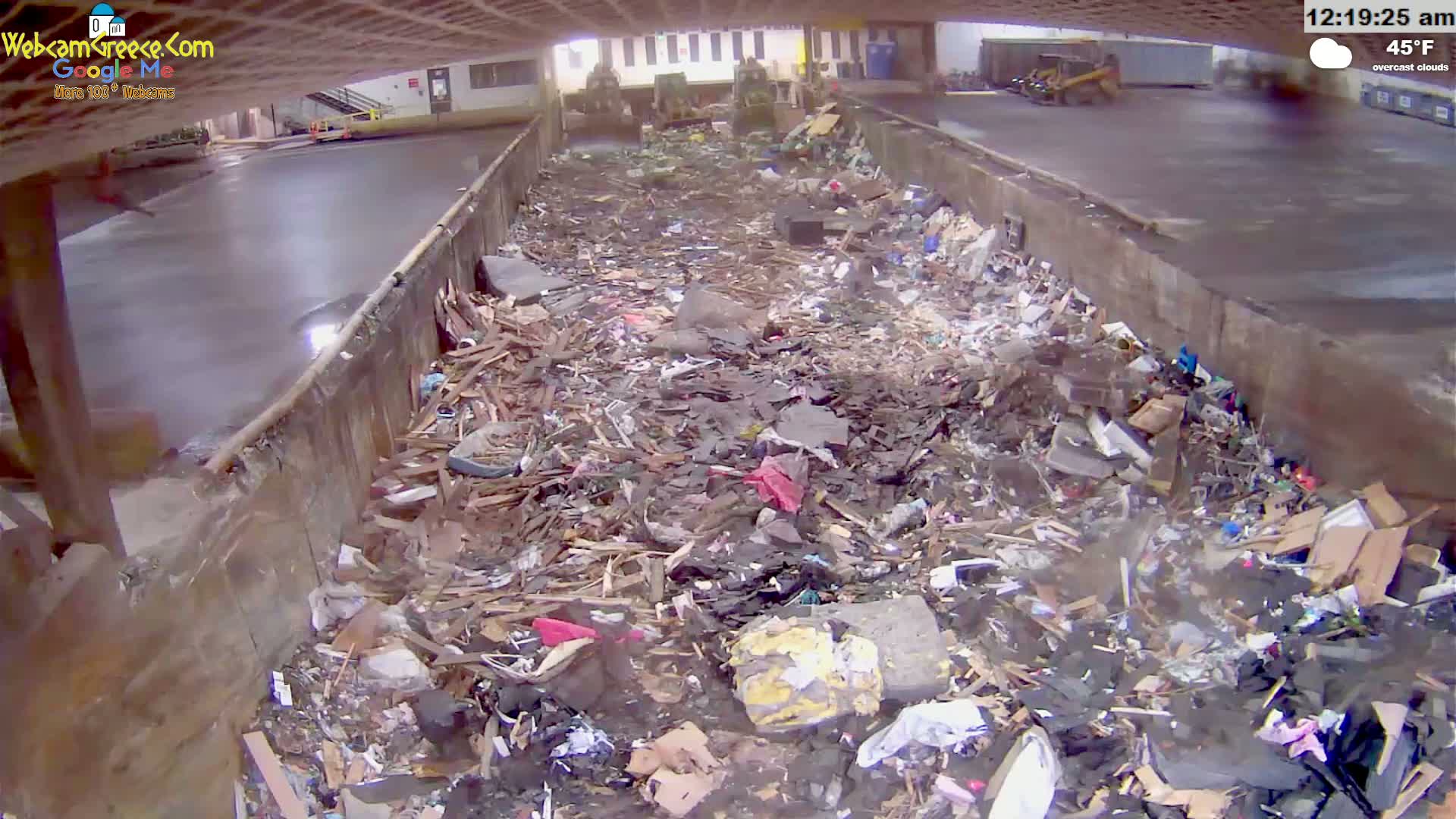 A large pile of refuse sits in an outdoor concrete pit under overcast skies.