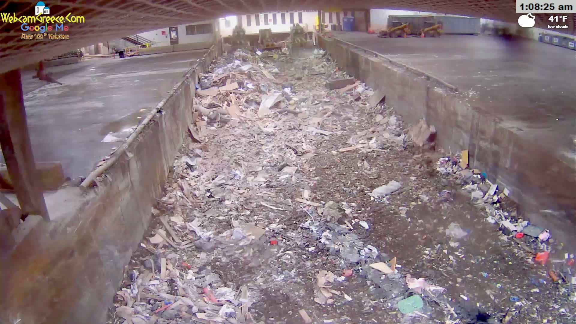 A long, concrete trough filled with a large pile of debris and scattered trash is seen under an overcast sky, with a temperature of 41°F.