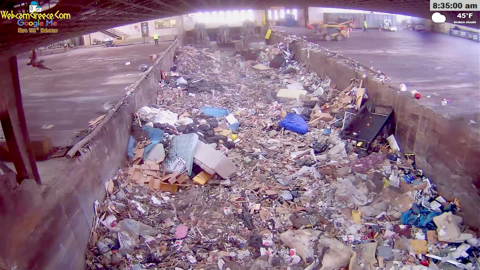 A large pile of garbage and debris fills a concrete trough under a partly cloudy sky, with a temperature of 45°F.