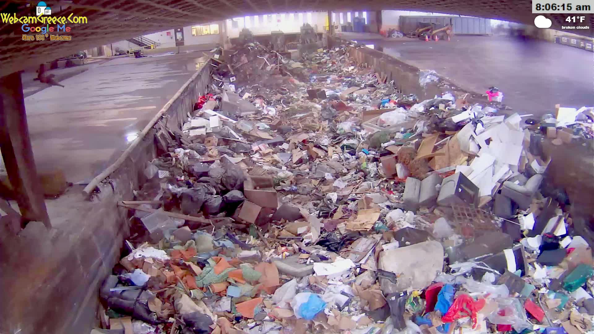 A large dumpster is overflowing with a variety of trash and debris under broken clouds on a 41°F day.