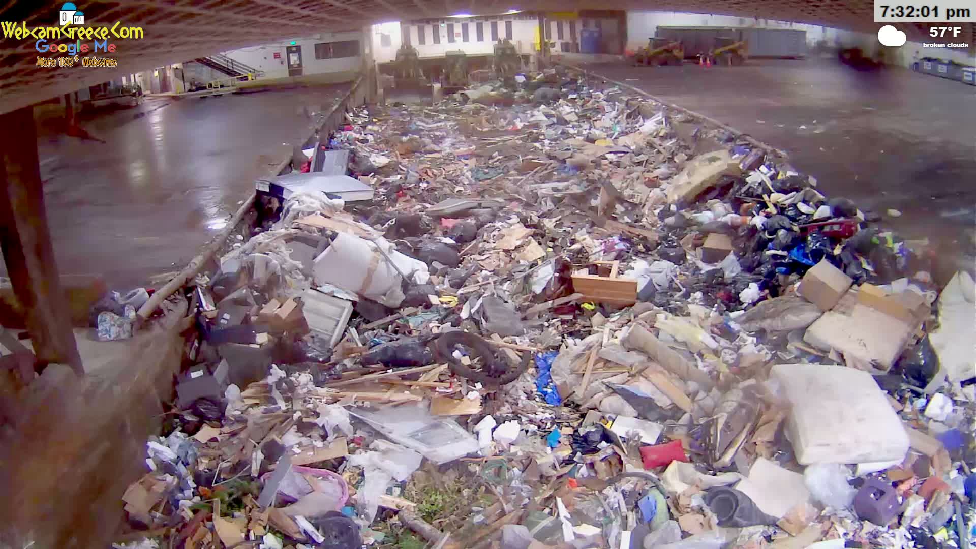 A large pile of mixed garbage, including furniture, cardboard boxes, and plastic items, is seen indoors under broken clouds at 57°F.