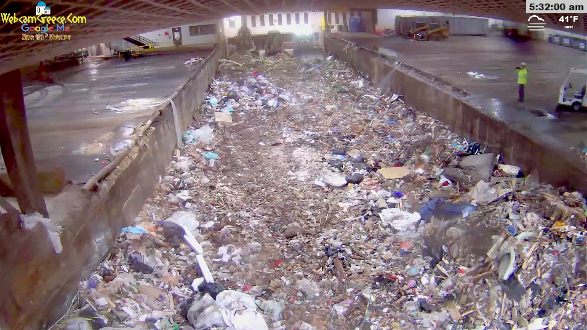 A large amount of trash and debris fills a long, narrow trough outdoors in misty, 41°F weather.