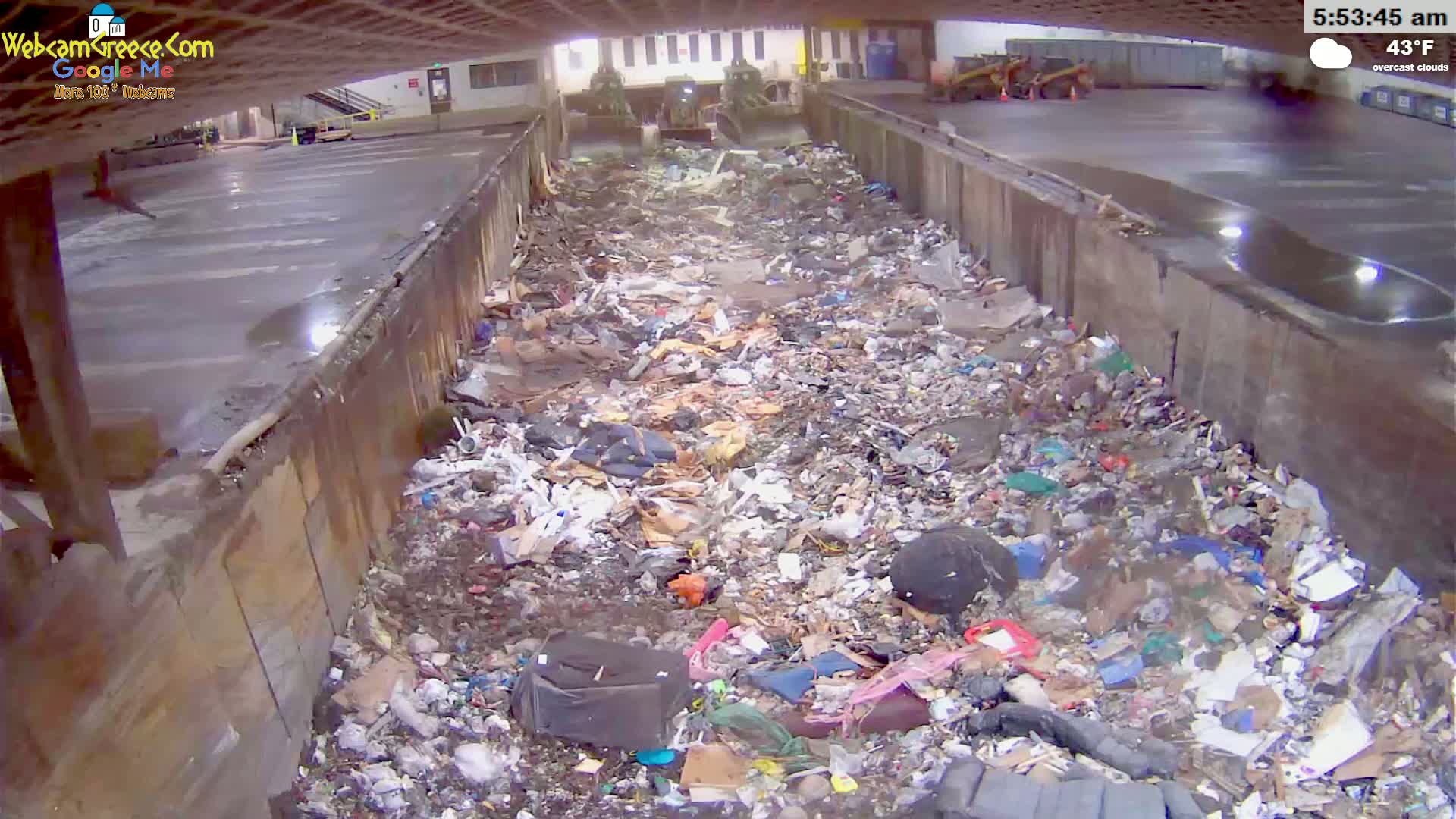 A large pile of trash is seen filling a concrete trough under overcast skies at 43°F.