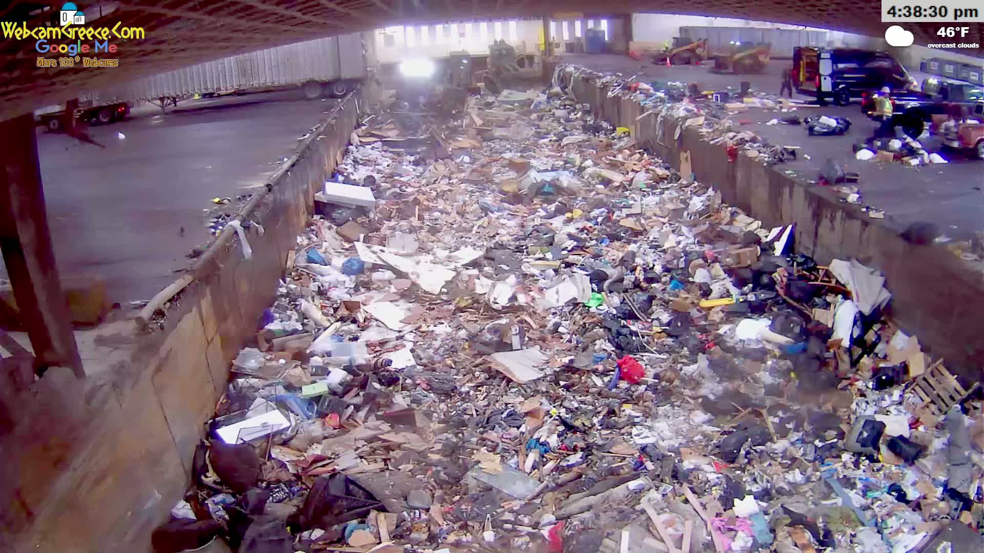 A large pile of trash is seen in an outdoor loading area under an overcast sky, with a temperature of 46°F.