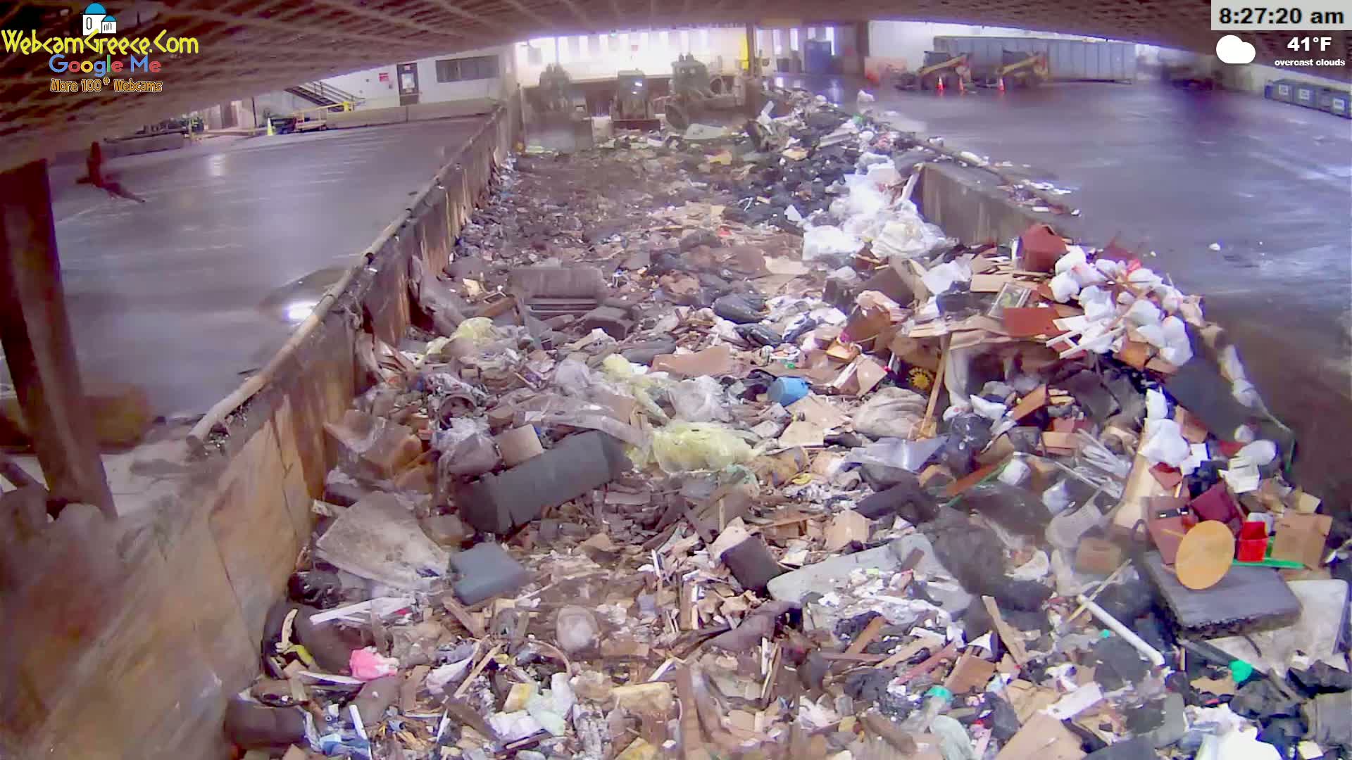 A large pile of assorted trash and debris fills a long, indoor receptacle under overcast skies, with the temperature at 41°F.