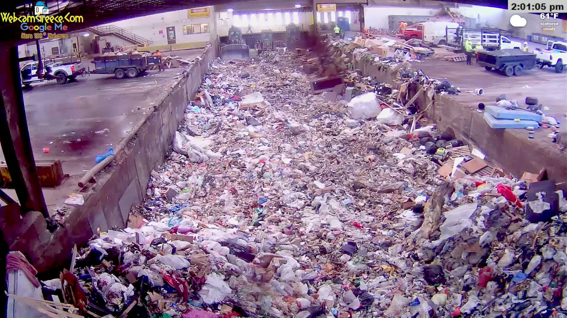 A large pile of trash fills a long, narrow concrete trough outdoors under scattered clouds.