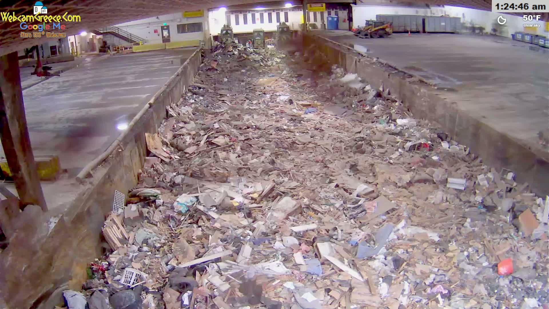 A large amount of debris and trash fills a long, narrow, concrete trough under a clear sky at 50°F.
