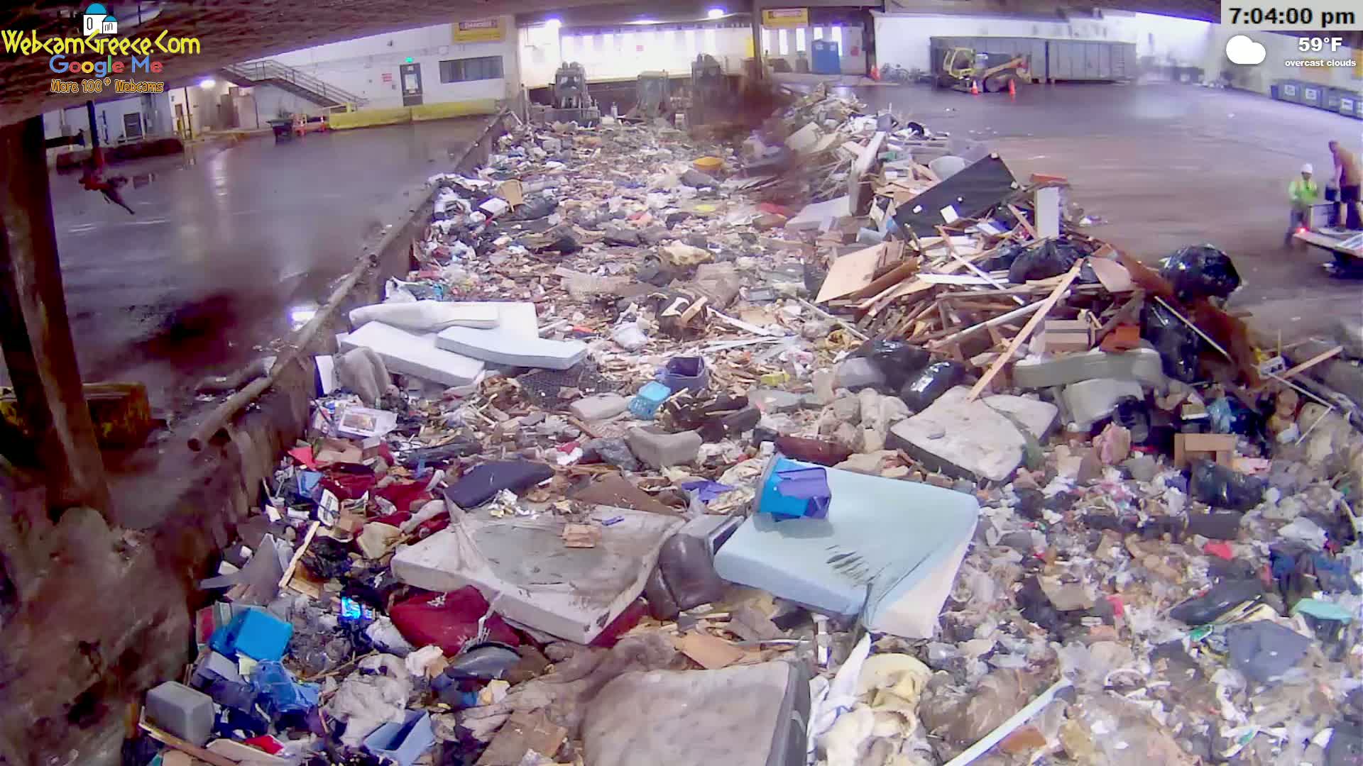 A large pile of discarded furniture, wood, and other debris sits in an outdoor, overcast area.