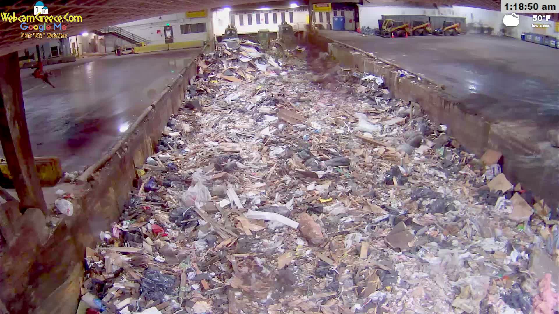 A large pile of trash sits in an indoor waste disposal area under a few clouds, with a temperature of 50°F.