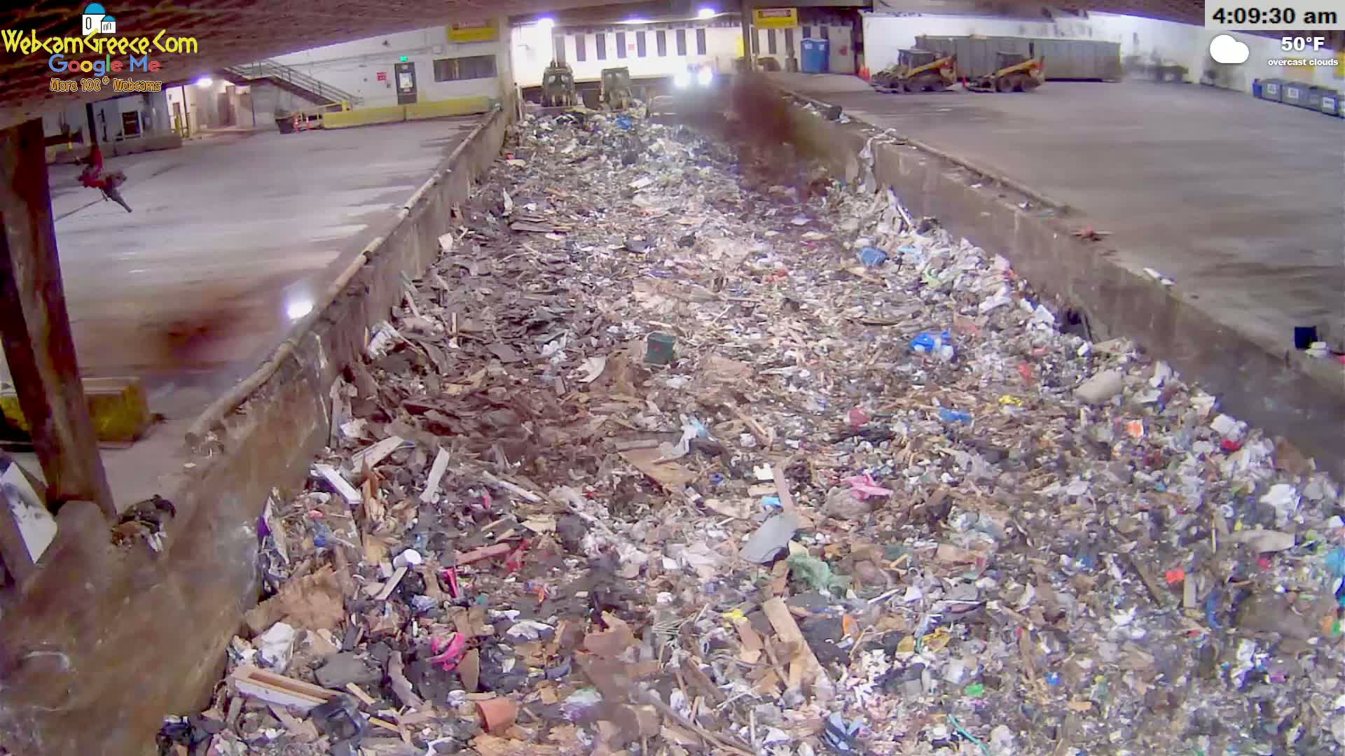 A large pile of trash sits in an indoor refuse container under overcast skies, with the temperature at 50°F.