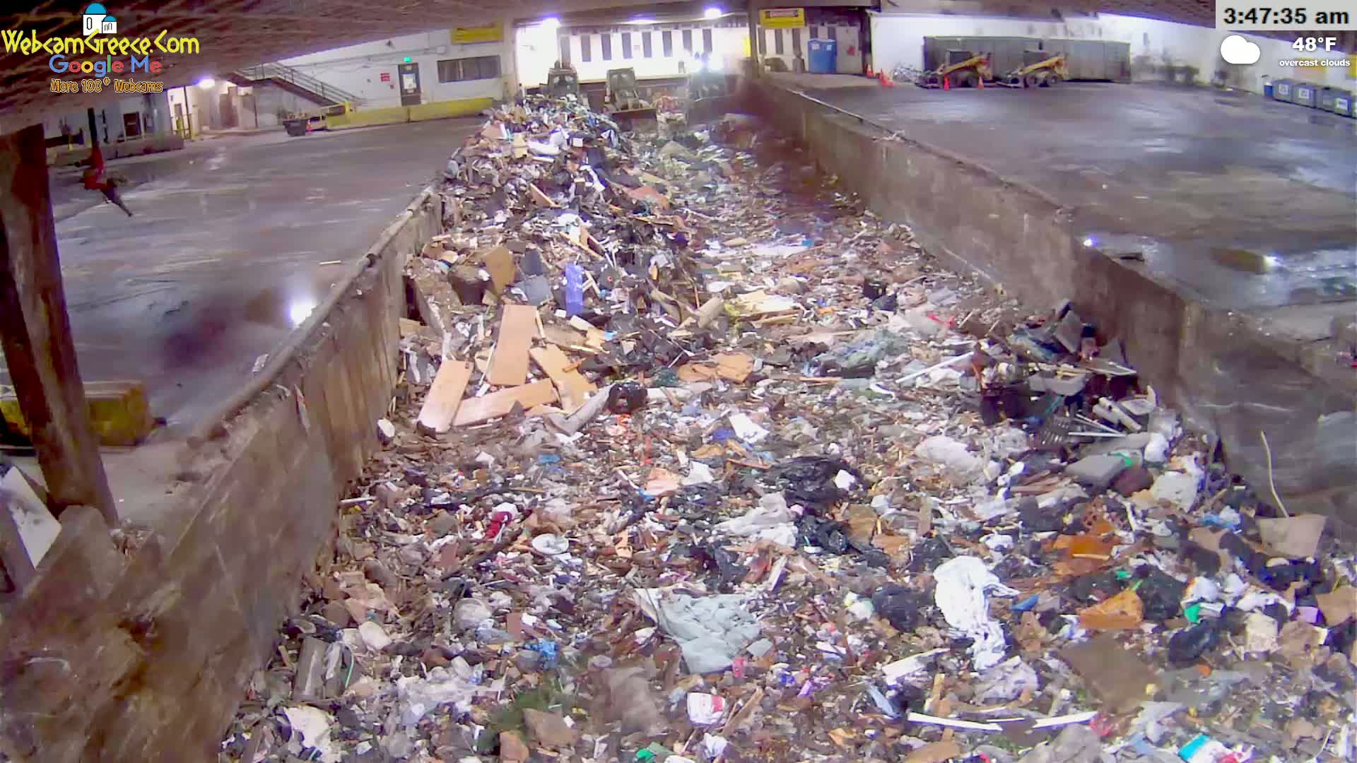 A large pile of refuse sits in an indoor waste disposal area under overcast skies at 48°F.