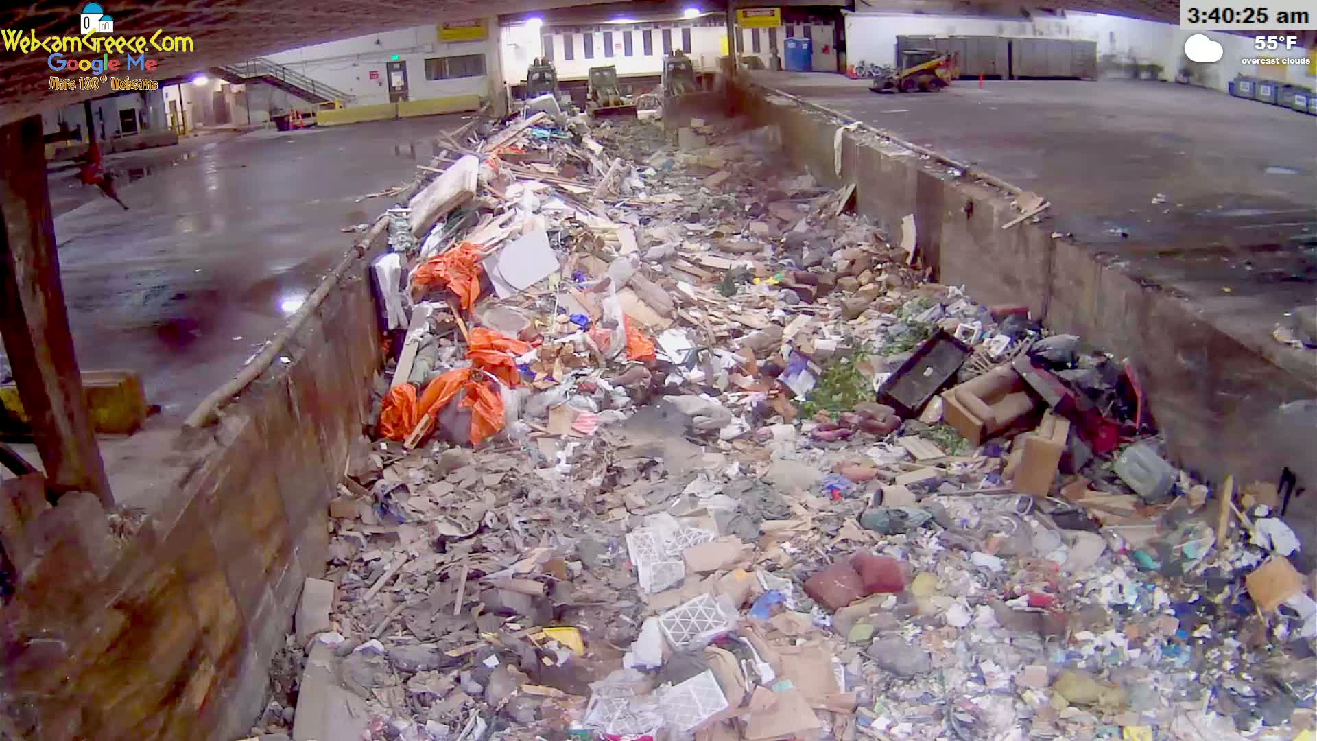A large pile of mixed garbage and debris sits within a concrete structure under overcast skies at 55°F.