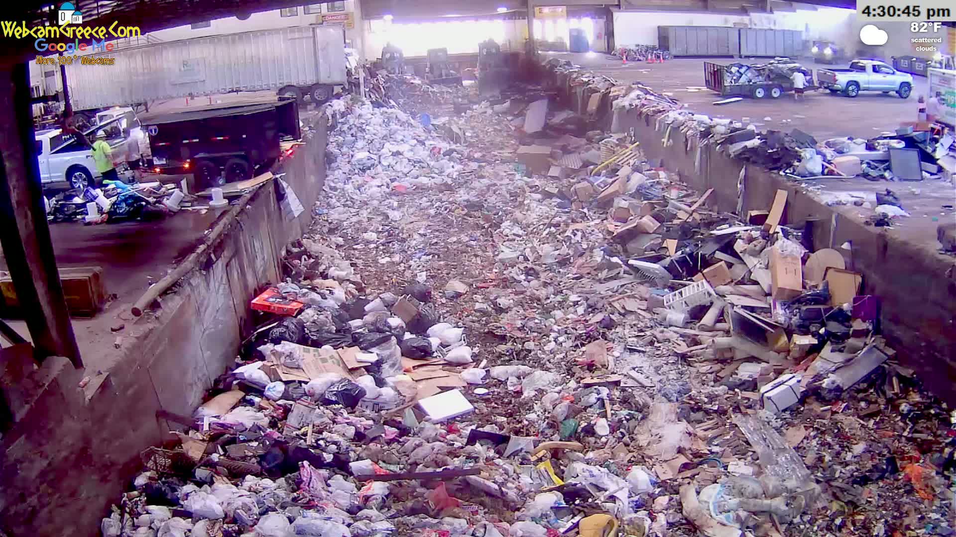 A large pile of trash and debris fills a long, narrow area outdoors under an overcast sky.