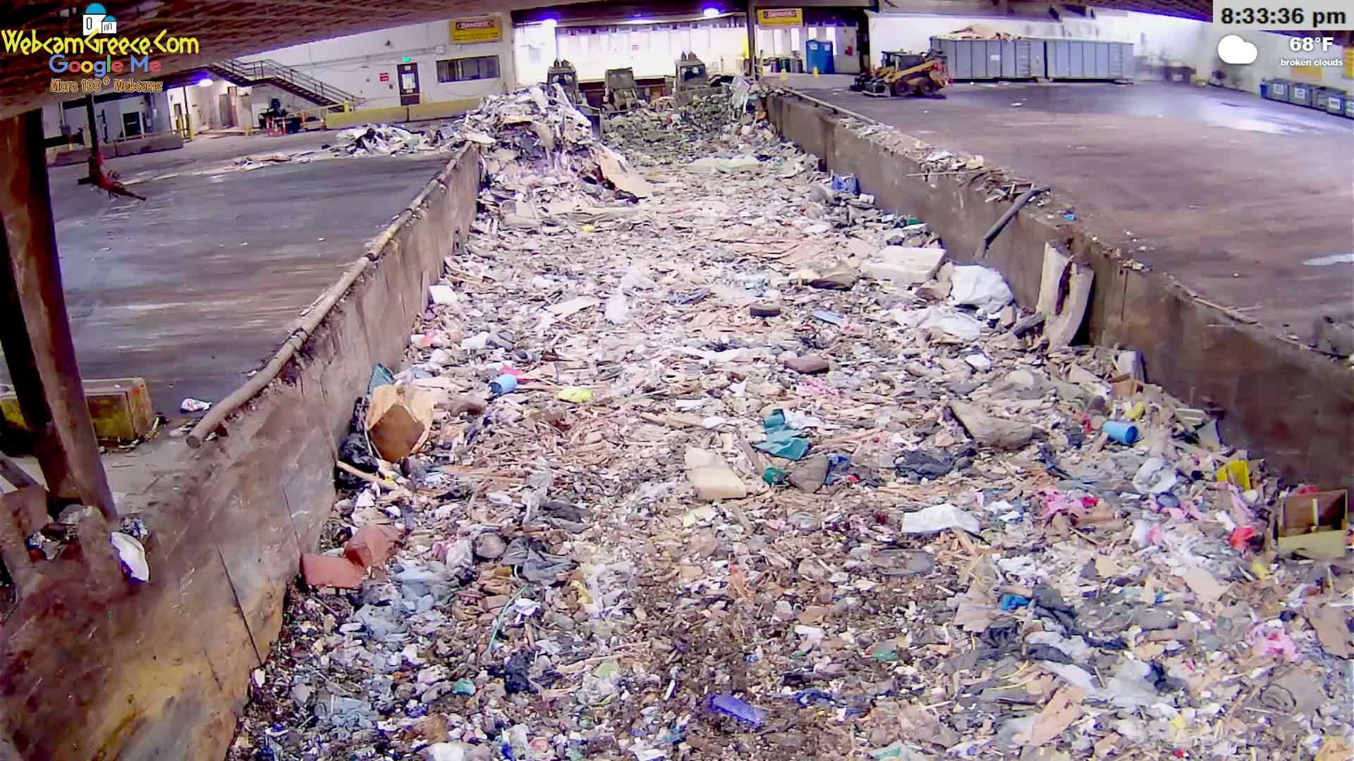 A large, open-topped container is filled with a substantial amount of mixed waste under a broken-cloud sky at 68°F.