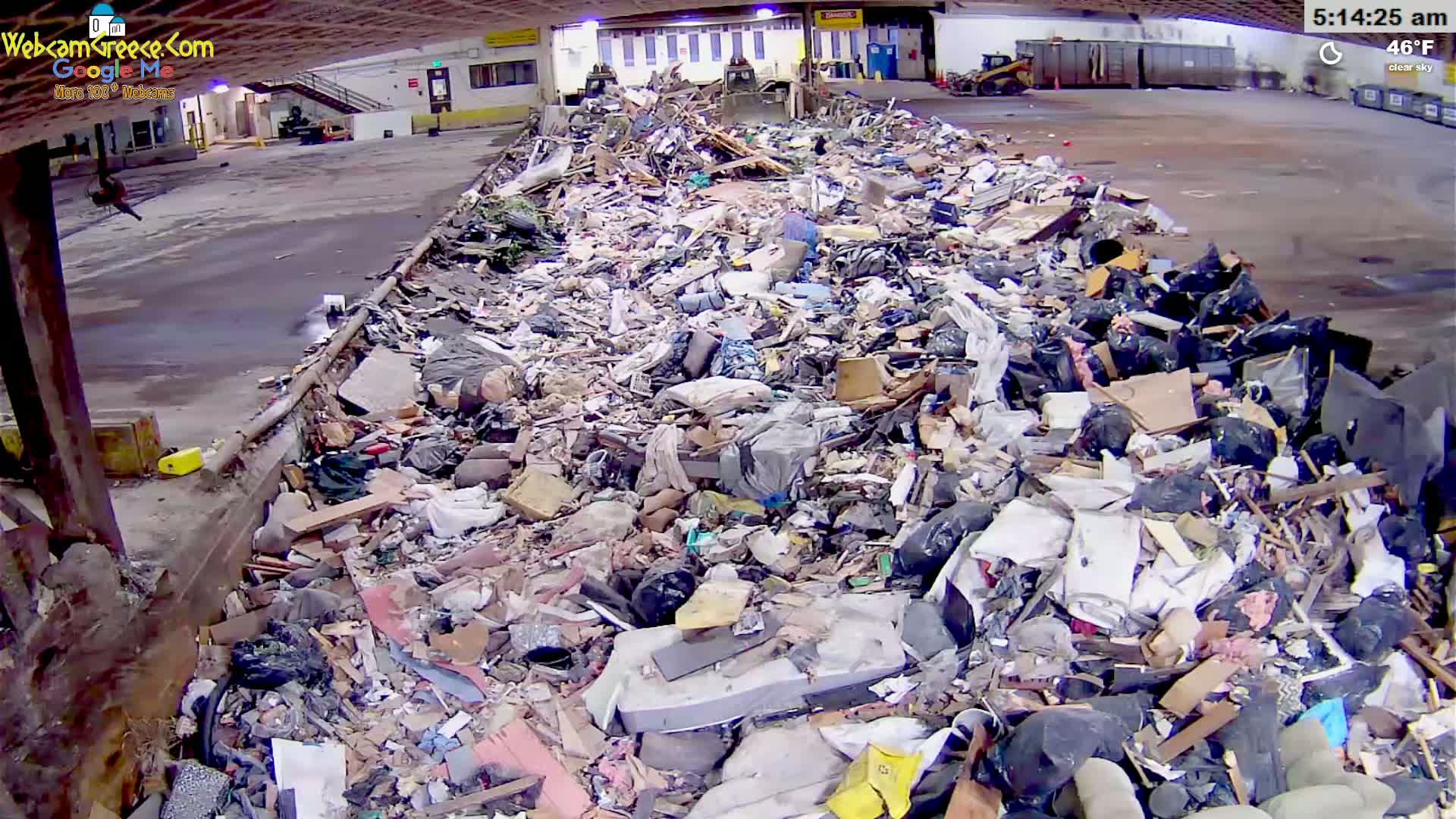 A large pile of mixed debris and trash sits inside a warehouse-like structure under a clear sky at 46°F.