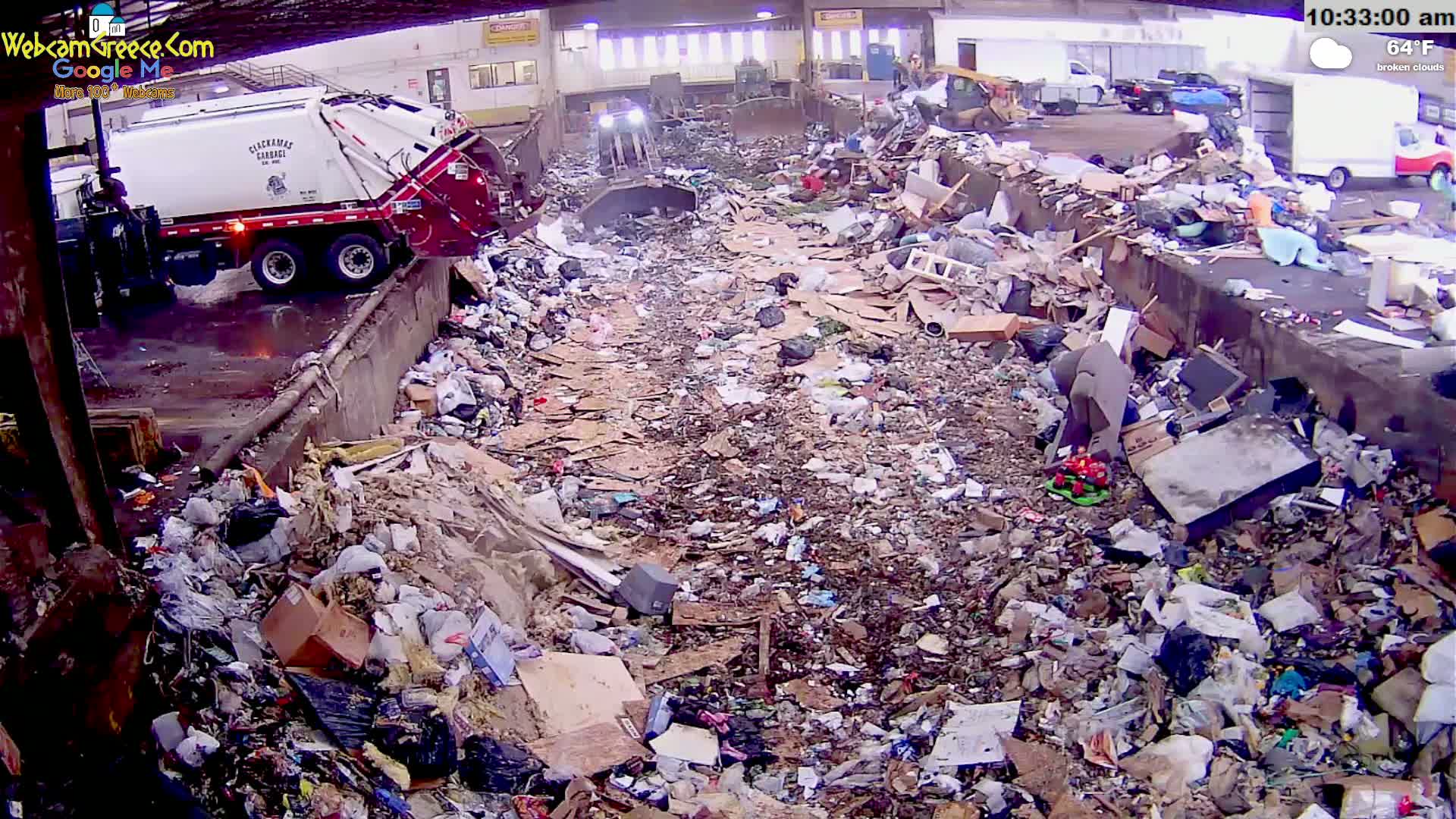 A garbage truck dumps its load into a large pile of refuse under a partly cloudy sky.