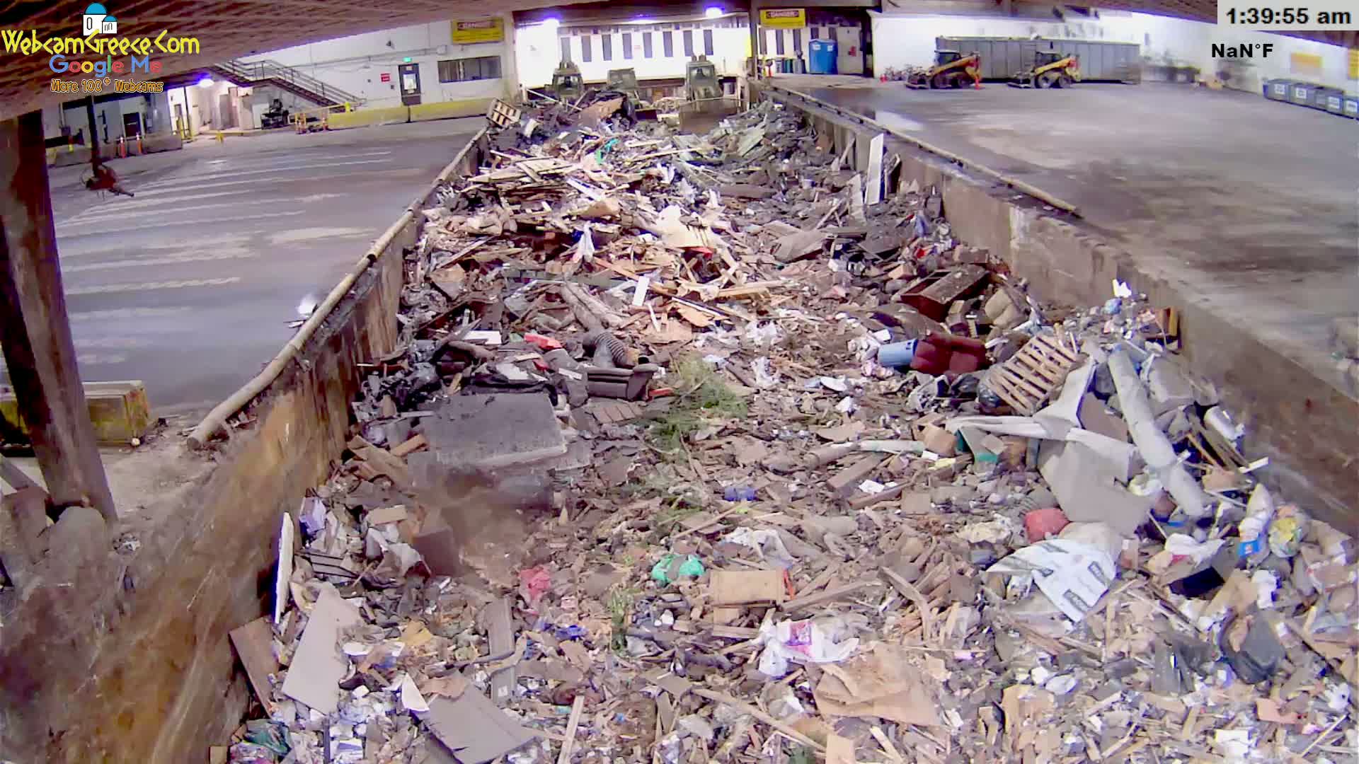 A large indoor bin is overflowing with a variety of construction and household debris.