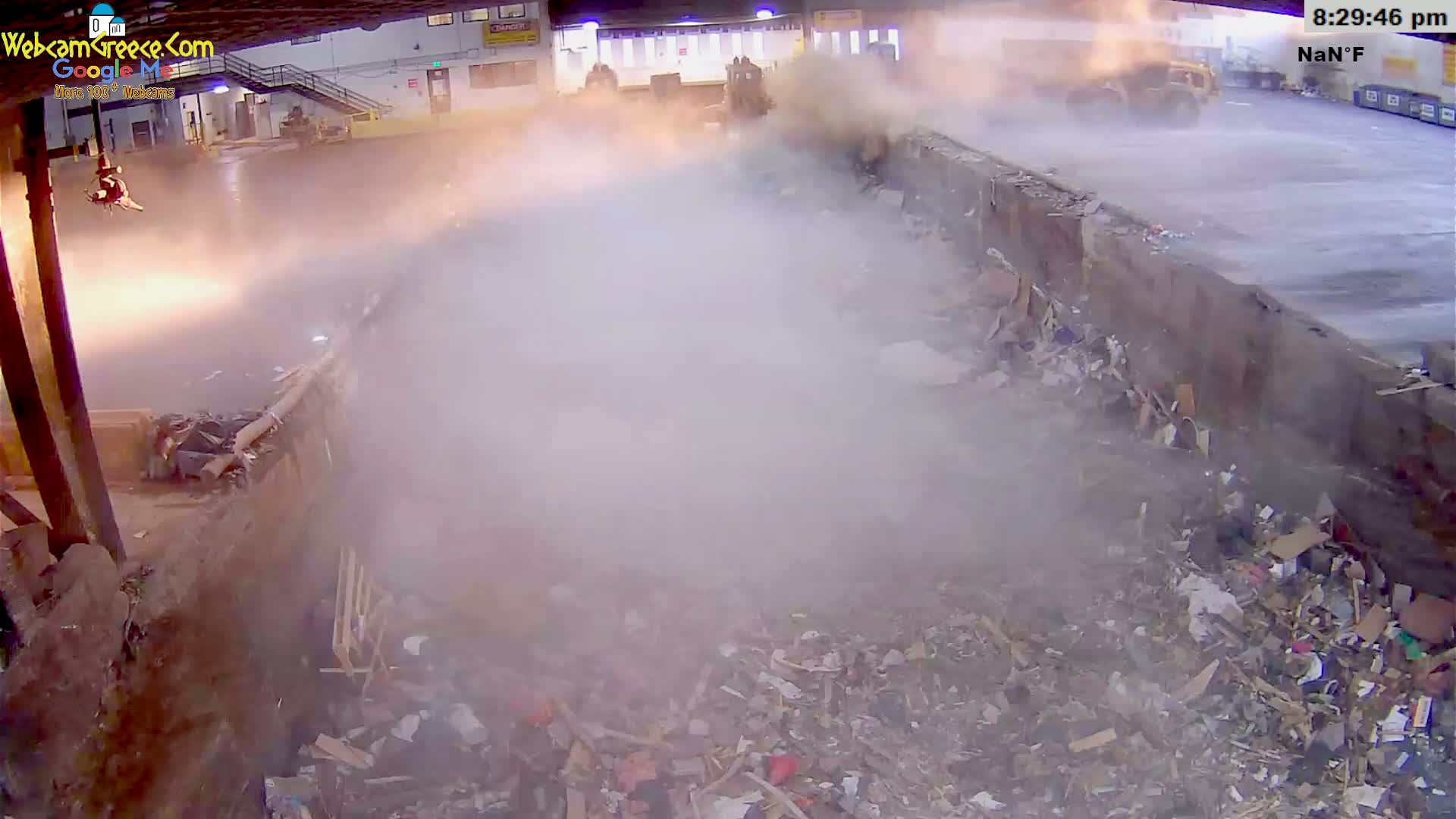 A large indoor bin is overflowing with a variety of construction and household debris.