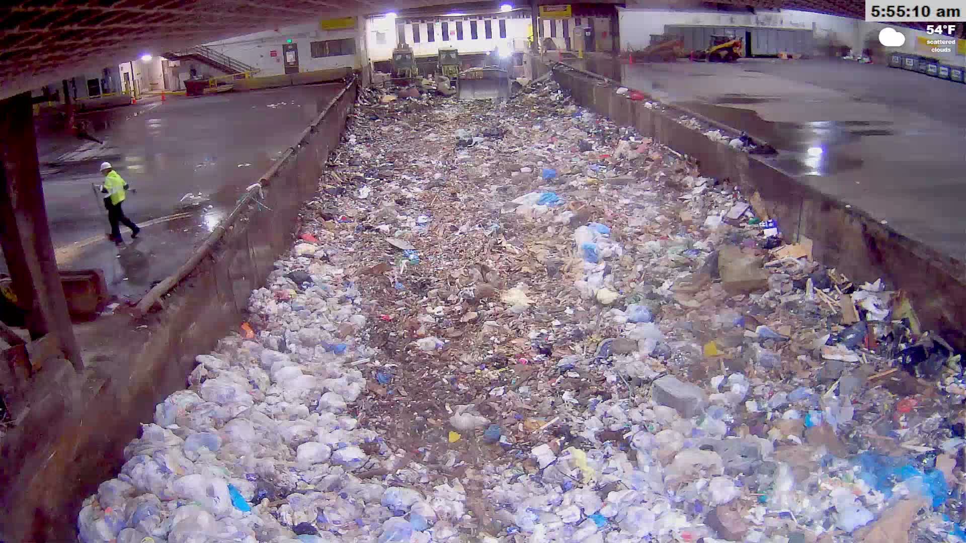 A large indoor bin is overflowing with a mixture of wood, debris, and other refuse.
